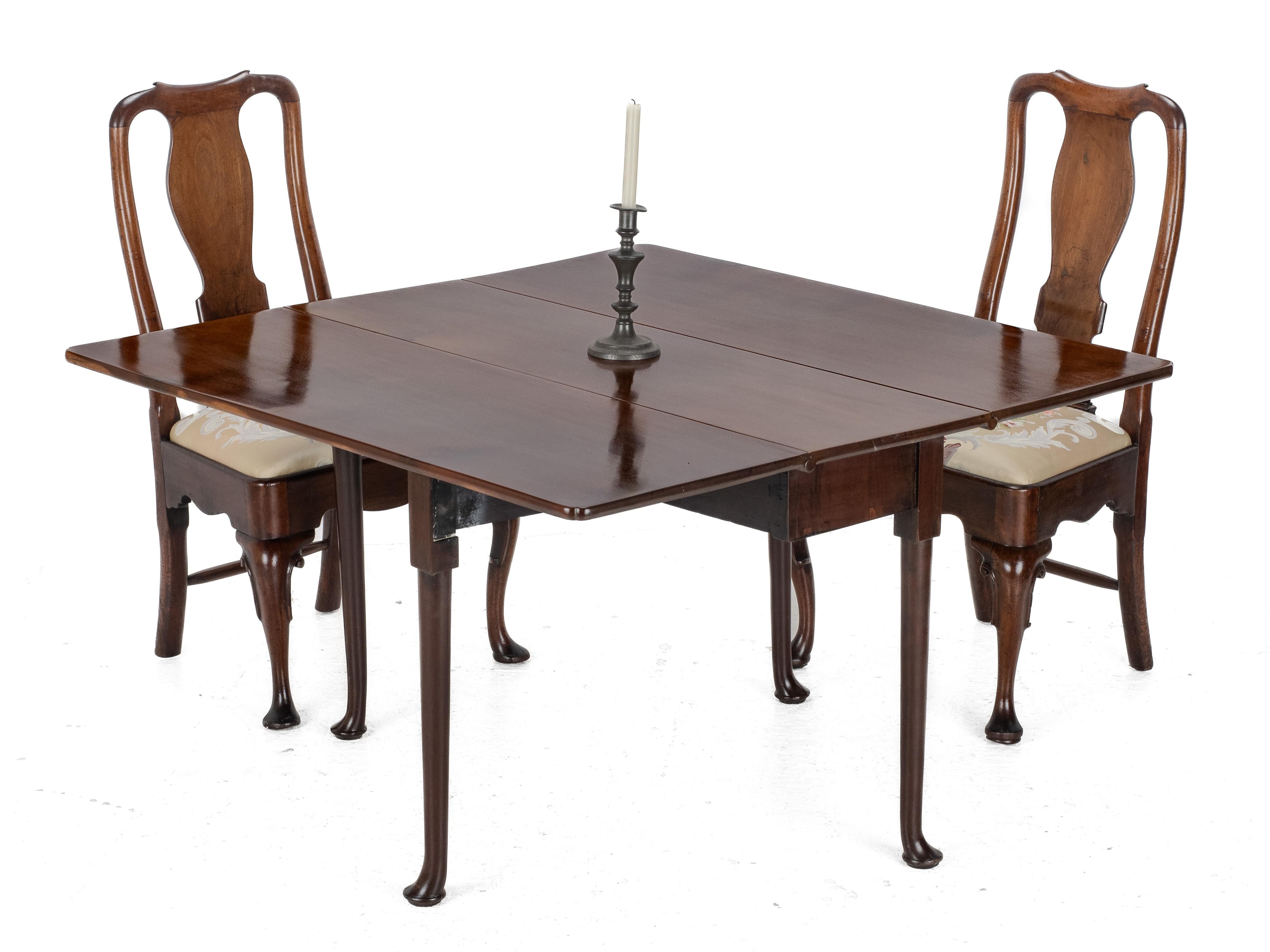 An early English walnut drop-leaf dining table, dating from the early 18th century (Queen Anne / Early Georgian period). The table features three solid, well-figured walnut leaves forming a near-square top with attractive double-lobed corners. The