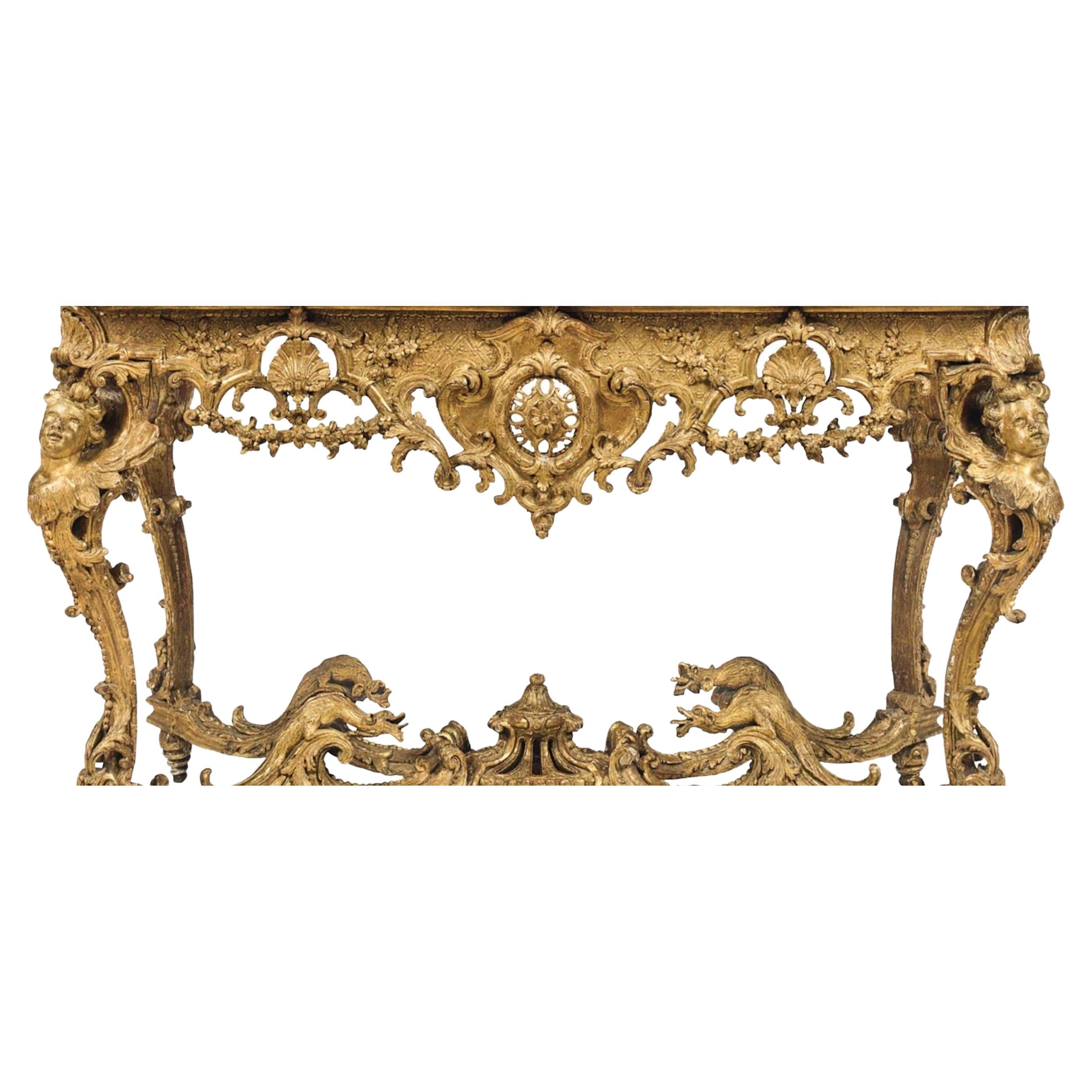 A regence giltwood console table was created in approximately 1720-1725. The later Siena marble top above a pierced carved frieze is decorated with floral swags, the bust-headed scrolled legs with wings are joined by a conforming X-stretcher with