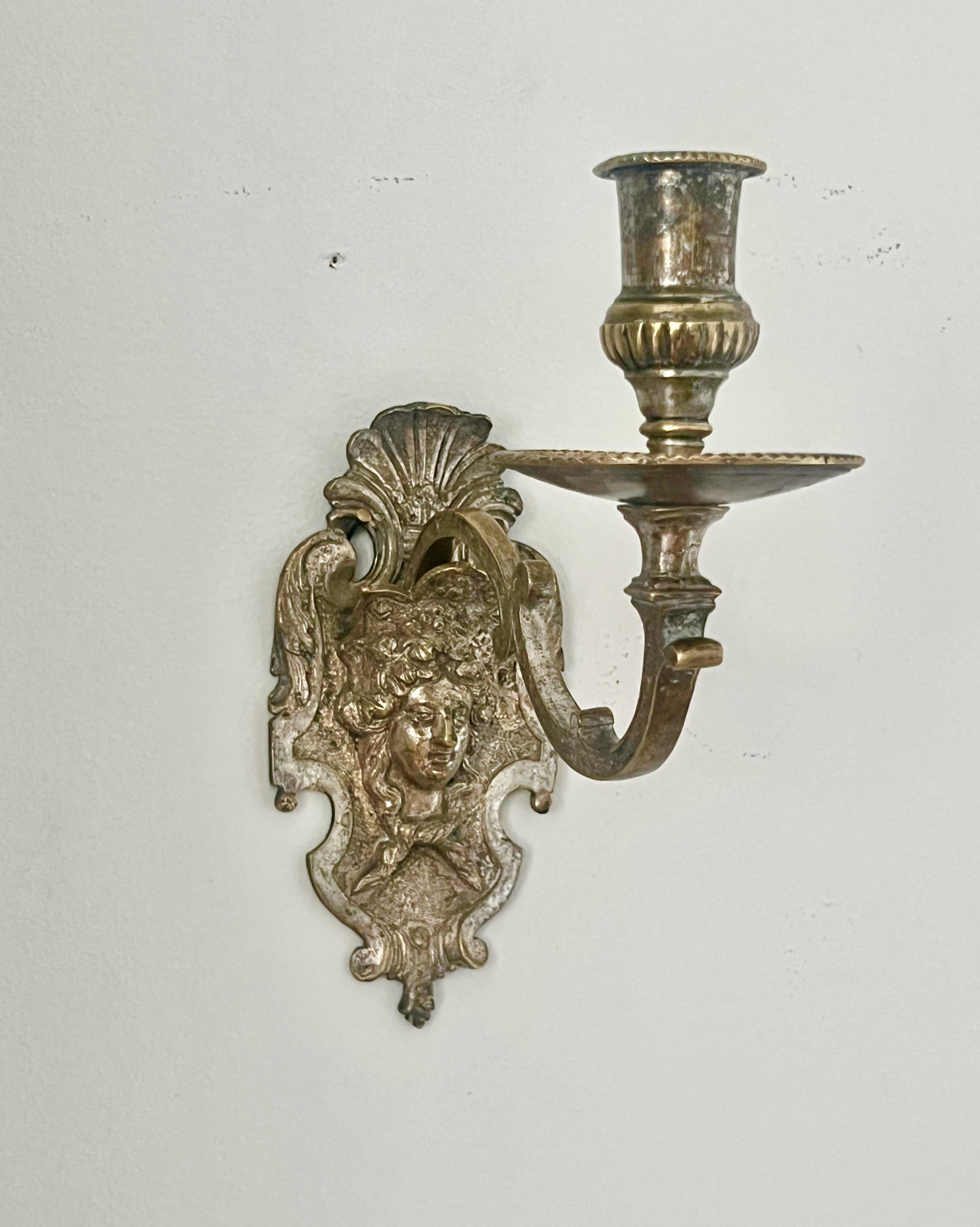 A French silver-plated bronze appliqué from around 1700 for a single light. The wall mount is richly decorated with a shell and acanthus motif, with finely punched grounds, surmounted by a mascaron portraying Louis XIV as the wine-god Bacchus. From
