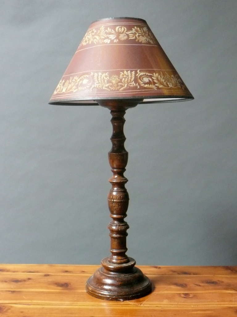 This 18th century repurposed French Provincial candlestick table lamp is made of boldly turned beech with a deep rich color and lustrous patination. The candlestick has been converted to a lamp and finished with a hand painted shade. South West