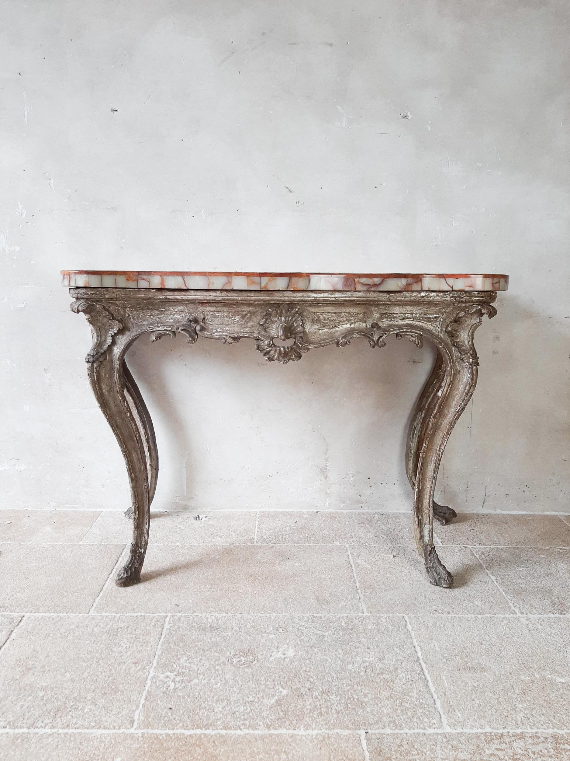 An 18th century Rococo style console table. A beautiful antique carved wood and gesso table with old golden patina and a top from Onyx marble in creme and red / amber tonesen.

Measures: H 86 x W 133 x D 68 cm.