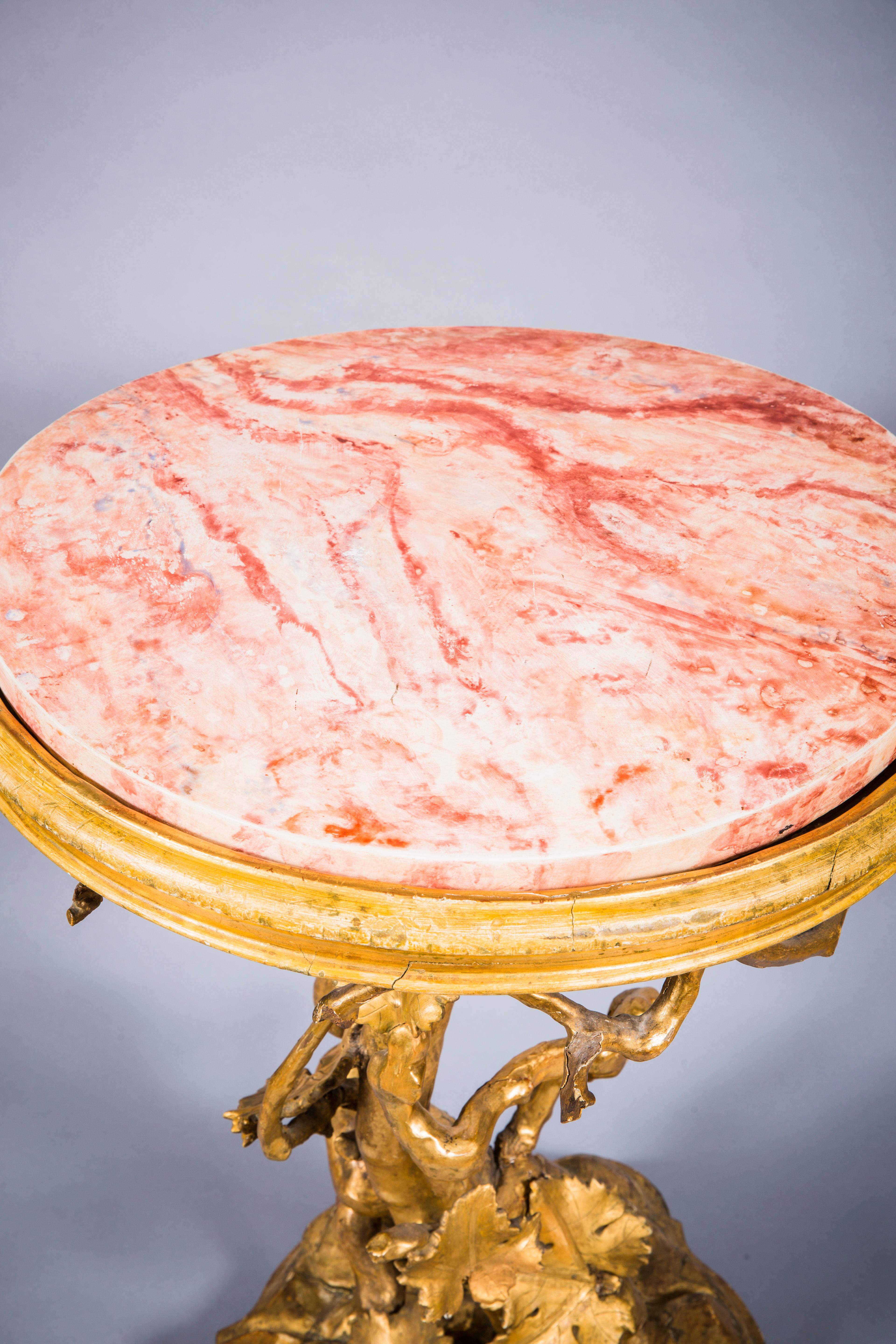 Table romaine rococo en bois doré
Italie, XVIIIe siècle 
Le plateau circulaire en faux marbre surmonté d'une vigne en feuilles de raisin repose sur une base en rocaille. Hauteur 32 3/4 pouces (83,3 cm), diamètre 22 1/2 pouces (57,2 cm). 

IVN : 3464
