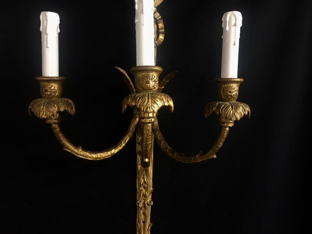 An impressive pair of Rococo French giltwood wall lights. Each is carved with feathers, tassels and ribbons, there are three arms on each sconce, holding three candle lights upon a holder nestled into carved feathers.
Standing at 29 inches in
