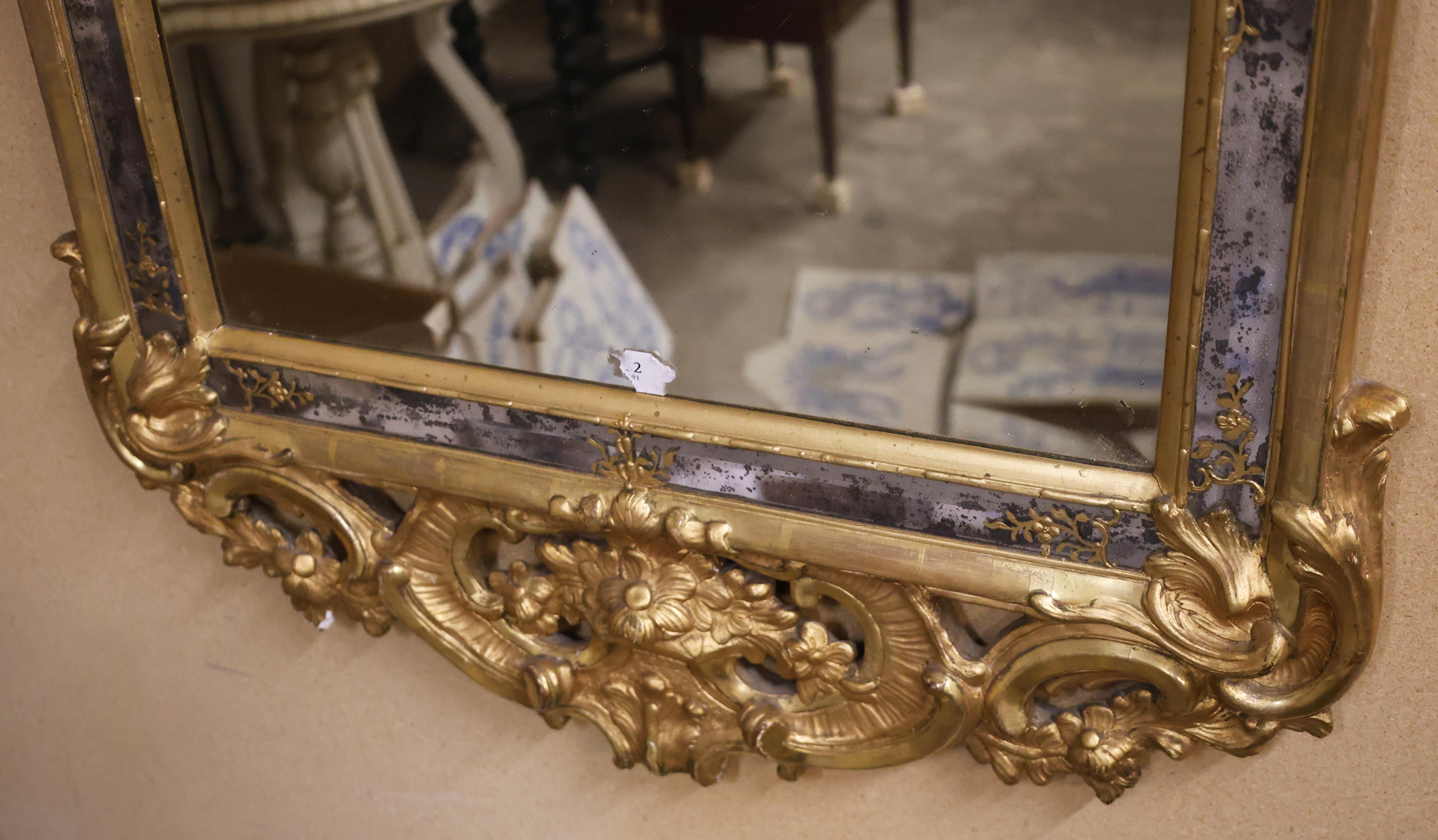 A high-quality gilded rococo mirror made in Stockholm, Sweden in the 1760s. The mirror's frame features beveled side glass with floral decoration in pastel shades. The central glass panels are also faceted. The top and bottom sections are richly