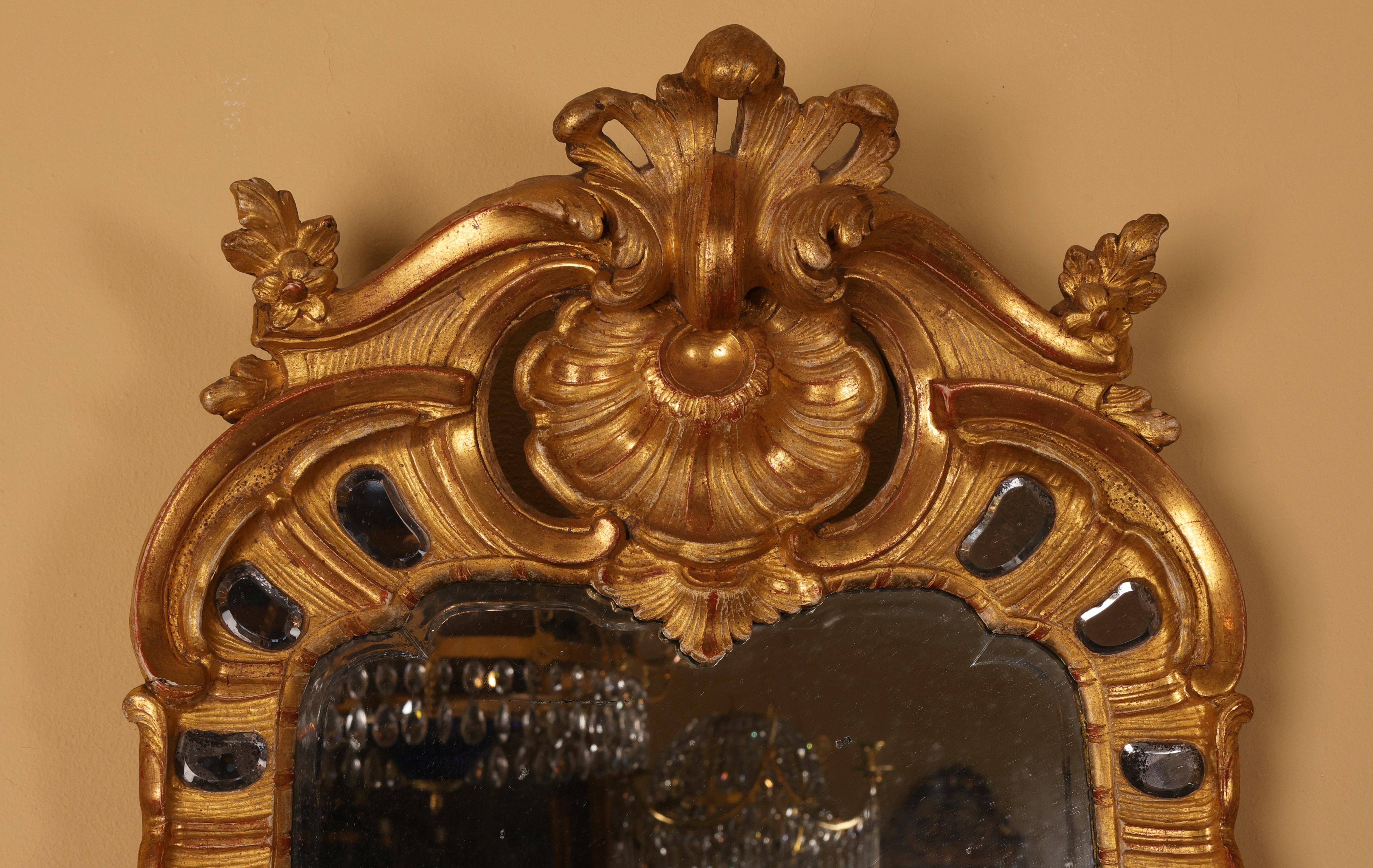 Miroir rococo de grande classe, fabriqué à Stockholm dans les années 1760. La monture est minutieusement sculptée et ornée de 30 lentilles à facettes, serties dans un cadre doré. La dorure est réalisée à l'aide de feuilles d'or véritable de