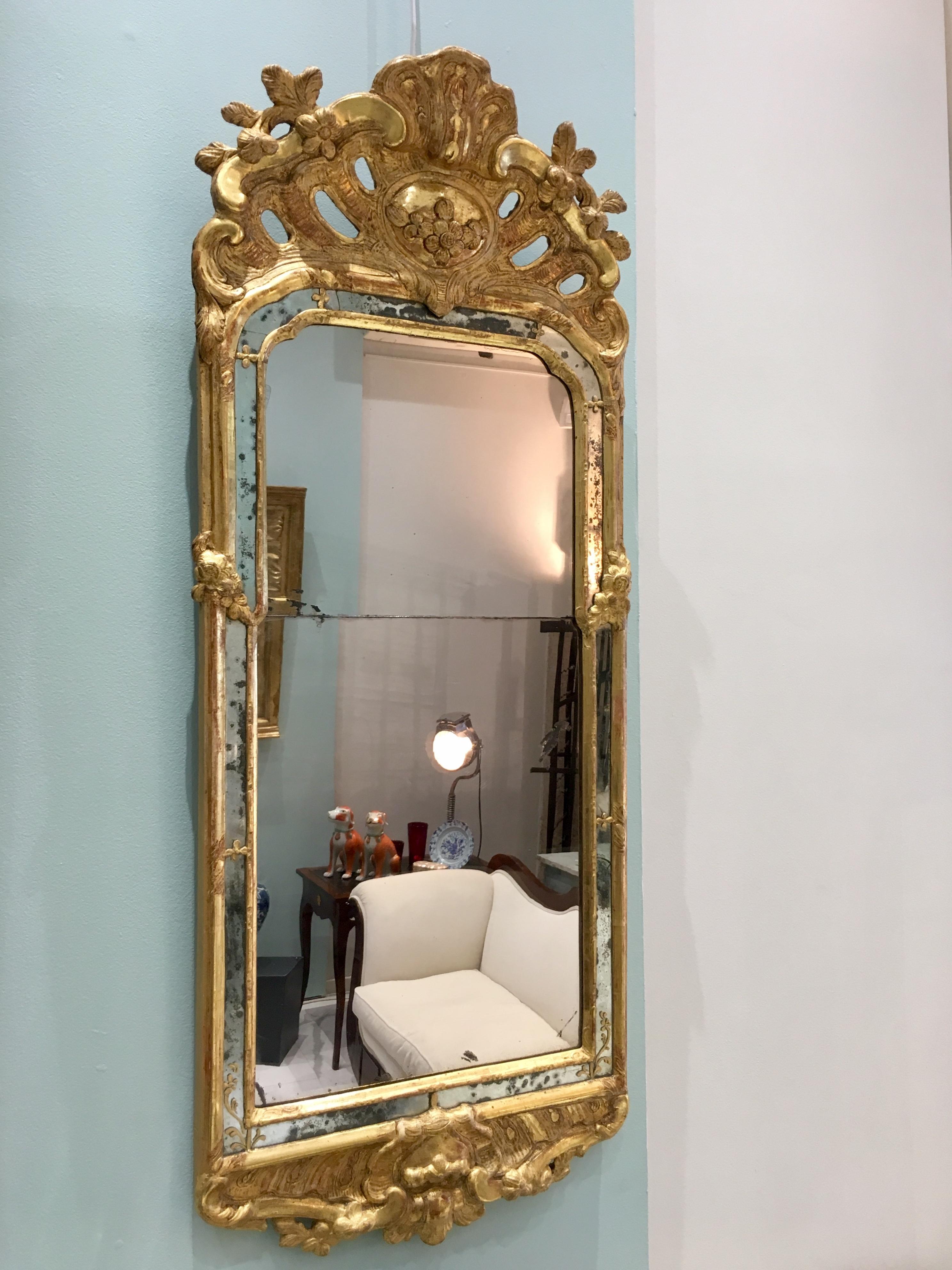 18th Century Rococo Swedish Mirror on Carved and Giltwood. Decorated with foliage motifs and crested by a shell and acanthus leaves. Around the main mirror plate, there is a mirror frame toped by delicate gilt carvings and painted floral