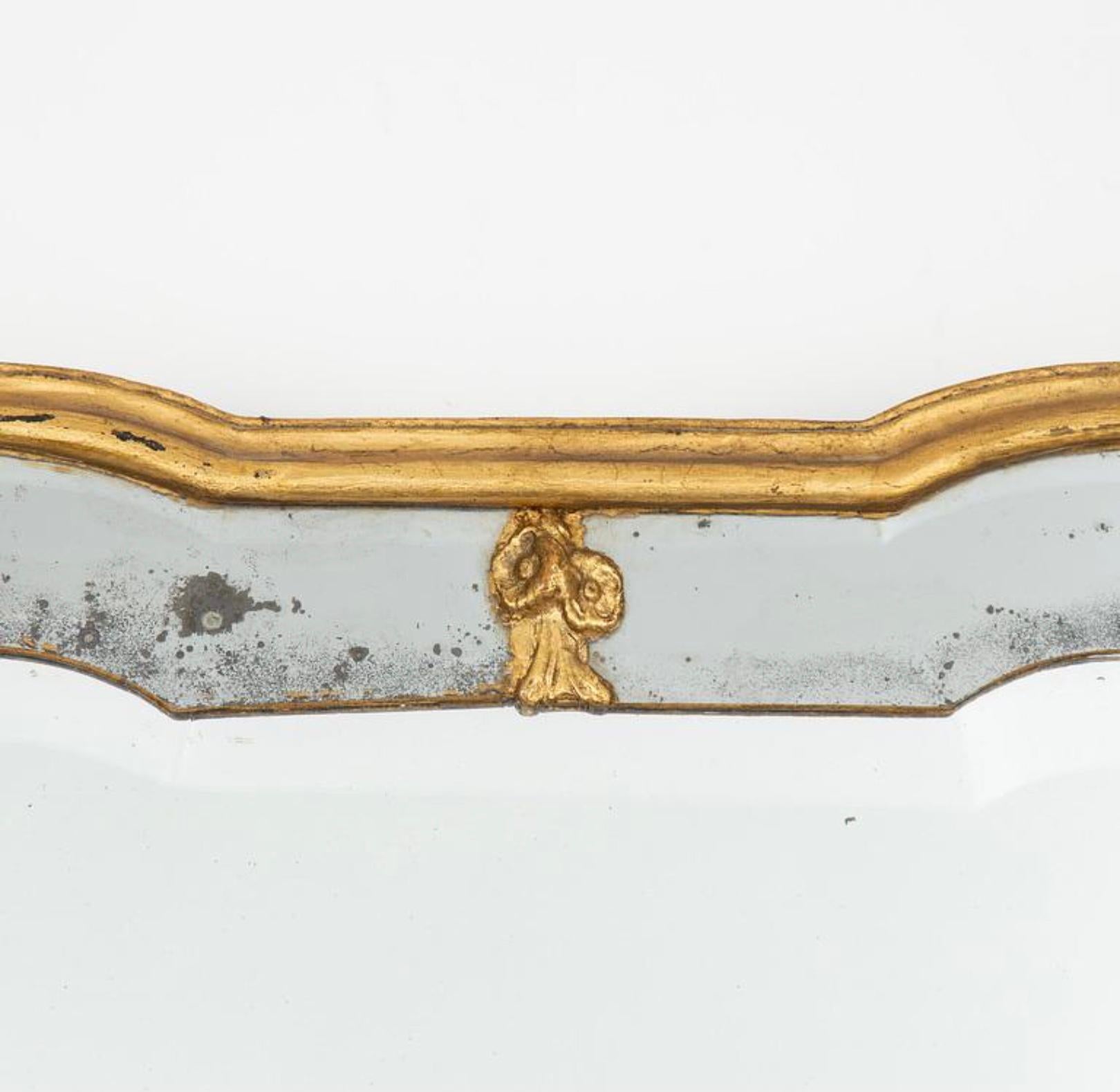 Affascinante e sobrio specchio rococò svedese del XVIII secolo bordato e incorniciato in doratura con bordo sfaccettato e semplici dettagli decorativi in gesso a forma di fiore; il vetro presenta un'usura e un foxing che conferiscono ulteriore