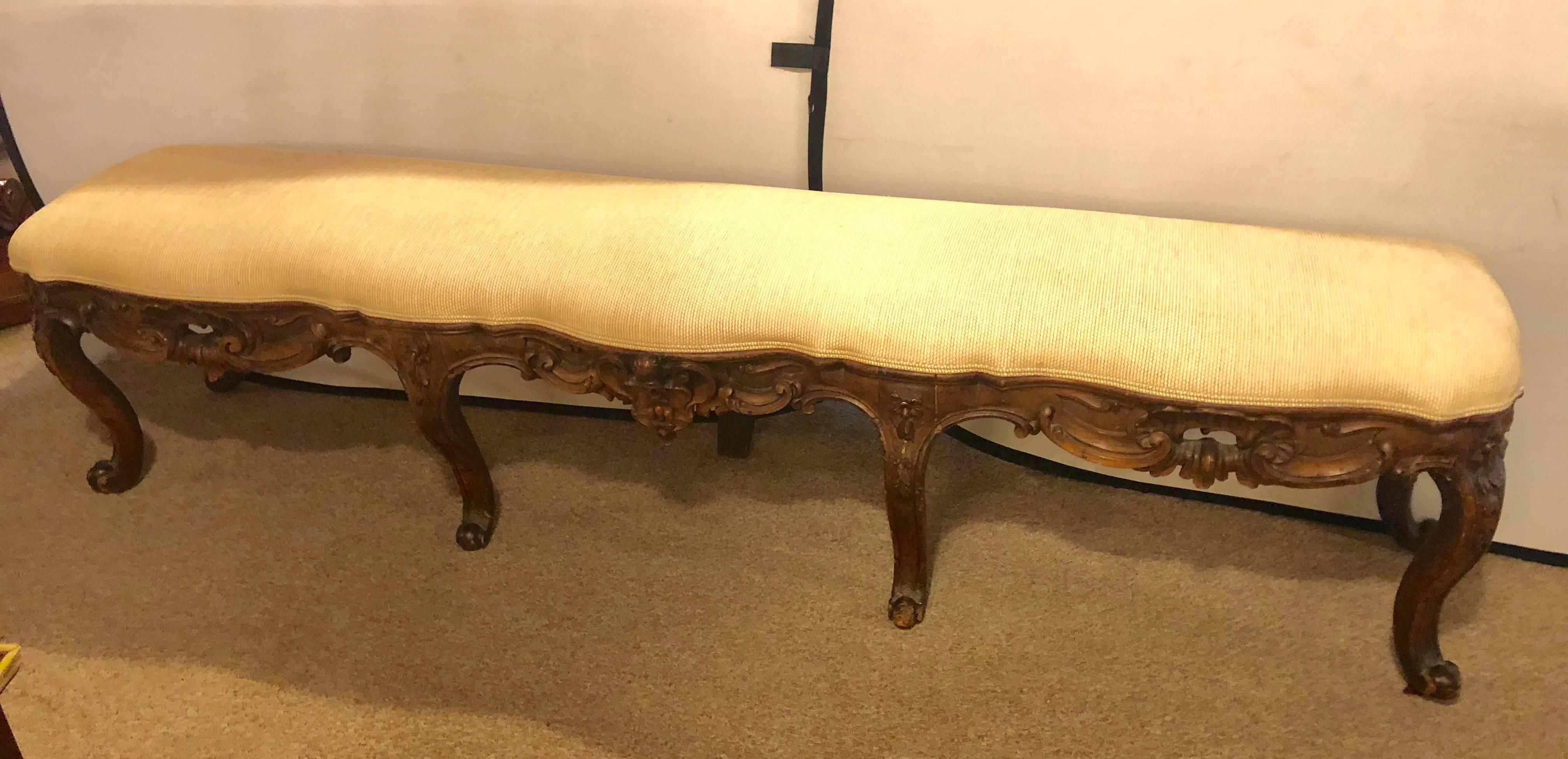 A 18th century Rococo window or bedside bench. Having four finely carved cabriole legs in the front supporting a carved apron. The whole having a fine tweed custom upholstered overstuffed seat.