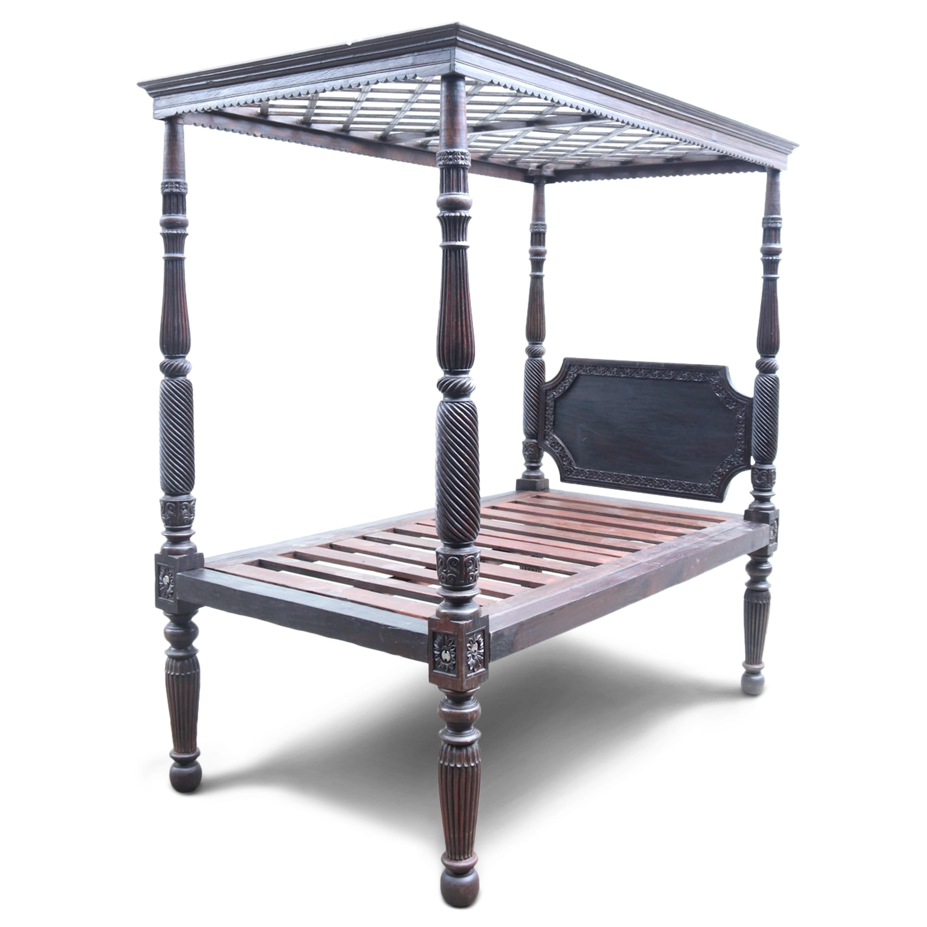 An 18th-century Rosewood tester/canopy bed originating from a significant palace in Goa. The bed features exquisitely carved posts, and the solid wood headboard contributes a blend of simplicity and robust elegance. Completing the regal presence of