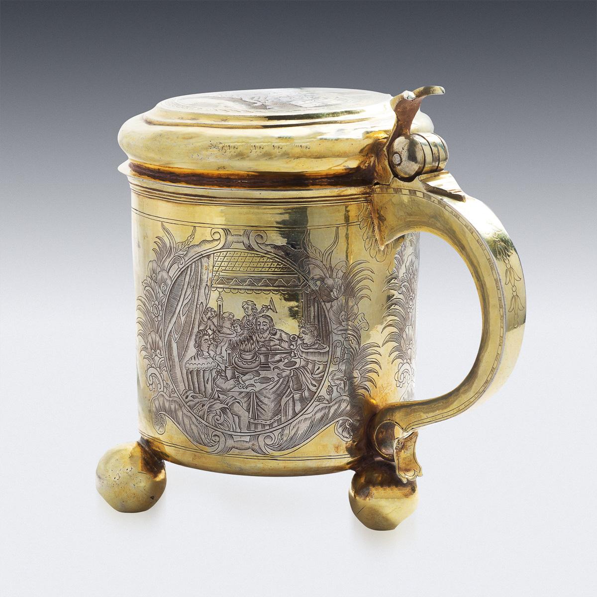 Antique mid-18th century Imperial Russian solid silver impressive lidded tankard, parcel gilt, of cylindrical form, on three ball feet, the body and hinged cover with four cartouches engraved with scene of Samson and Delilah: the body depicting
