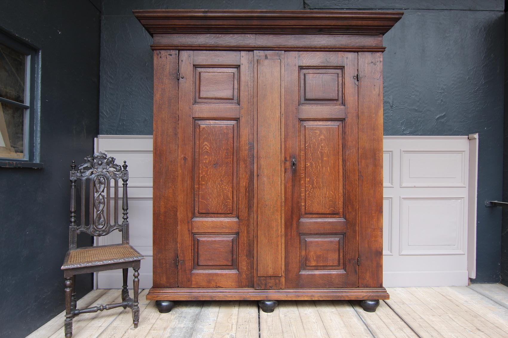 A 18th century cupboard, probably from the Herve region in Belgium.
Straight, 2-door oak body standing on ebonized ball feet. Both doors and side panels are made with panels. Multi-profiled header.

Equipped with 3 shelves inside. Of course,