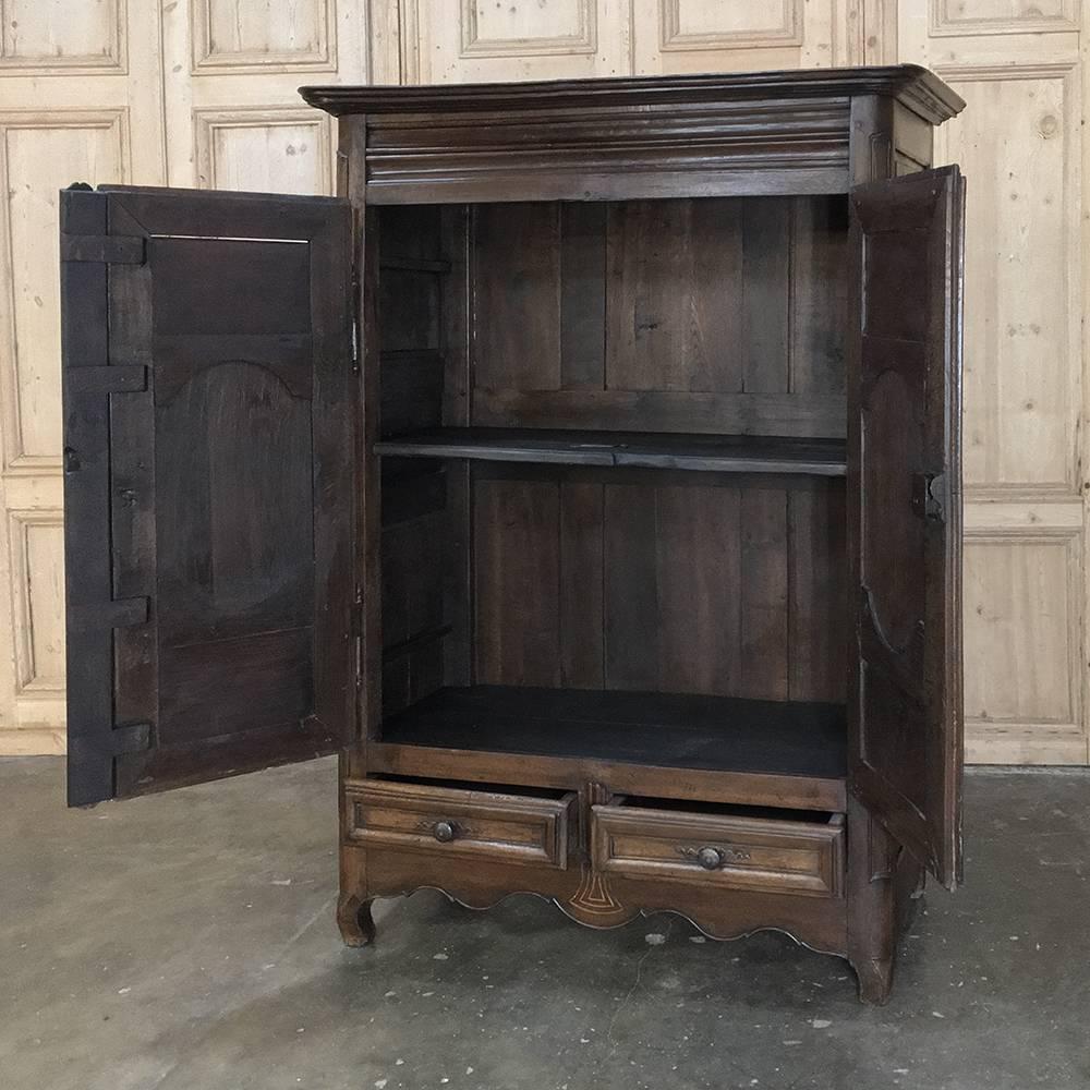 18th century rustic Country French oak armoire features a tailored architecture enhanced with subtle scrollwork on the frames around the chamfered door panels. A pair of external drawers below add stylish functionality. Doors open wide thanks to the