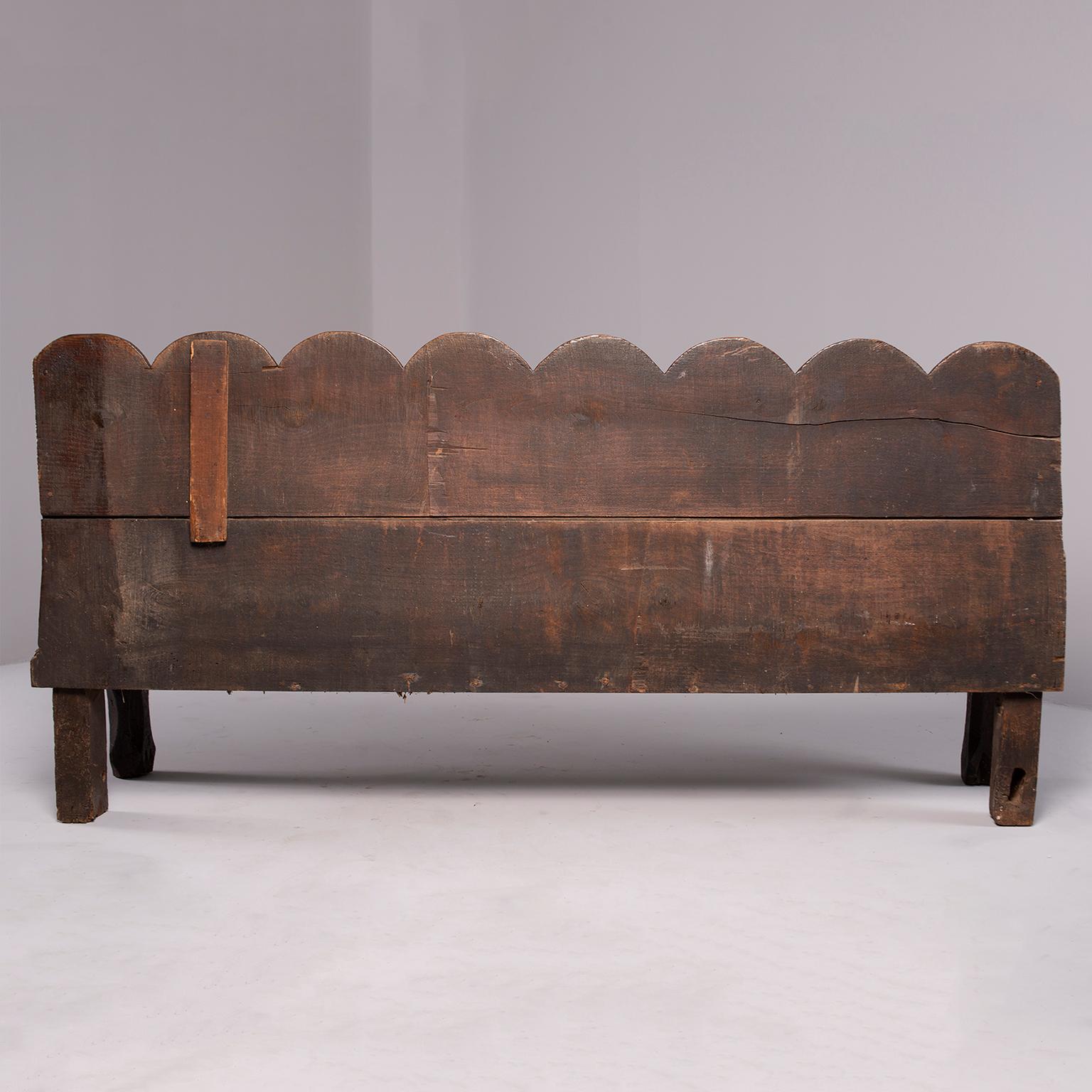 Hand-carved rustic Dutch chestnut bench has scallop edge detail on back rest, circa 1760s. Wood shows wear and patina and bench is structurally sound. Arms are 26” high and seat is 14.75” high and 19.25” deep.