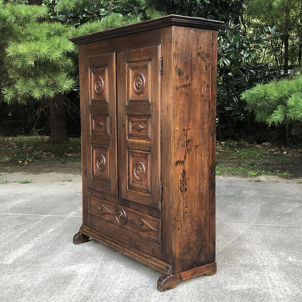18th century rustic Italian chestnut armoire is a splendid example of rustic classicism, with typical Italian attention to detail such as the shallow casework design augmented by extended feet below, a full width drawer adorned with tailored carved