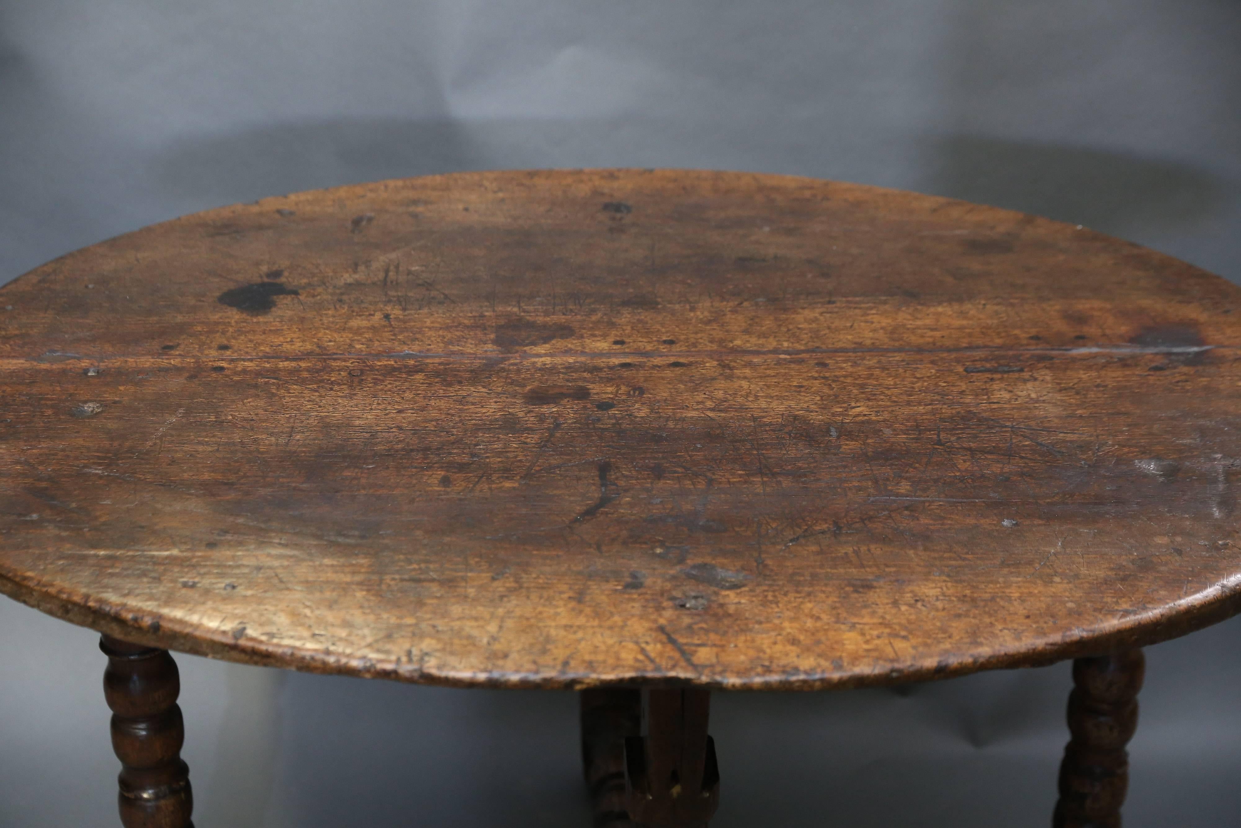 18th century oval wooden table with beautiful carved base. Pictures do not do justice to the patina. Edge of table only achieved through decades of use.
