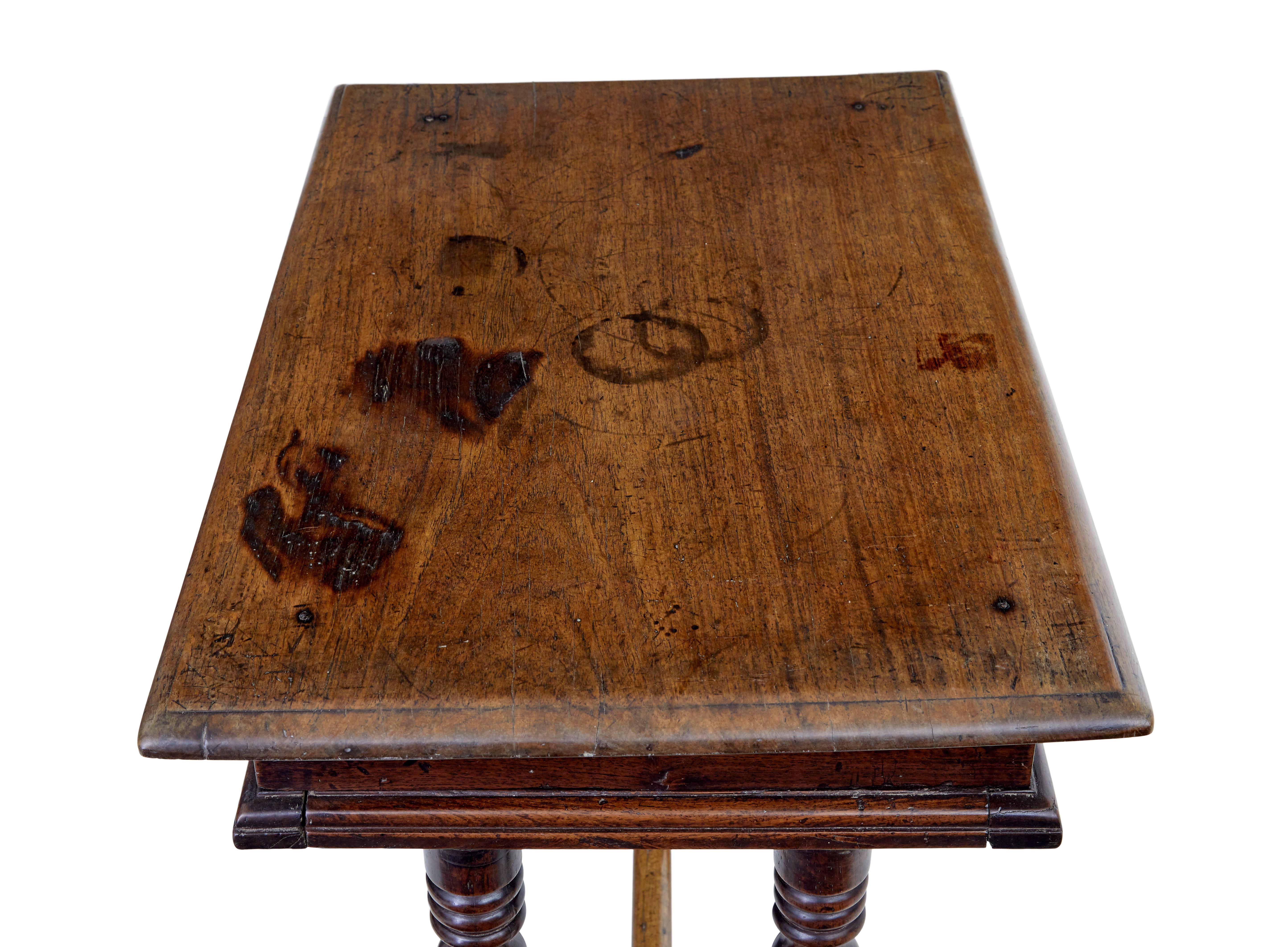Quirky rustic walnut side table, circa 1780.

Over-sailing top beneath which is a single drawer with 2 turned handles.

Standing on 4 turned legs and sledge feet, united by stretcher.

Lock missing to drawer, surface burns and staining to top,