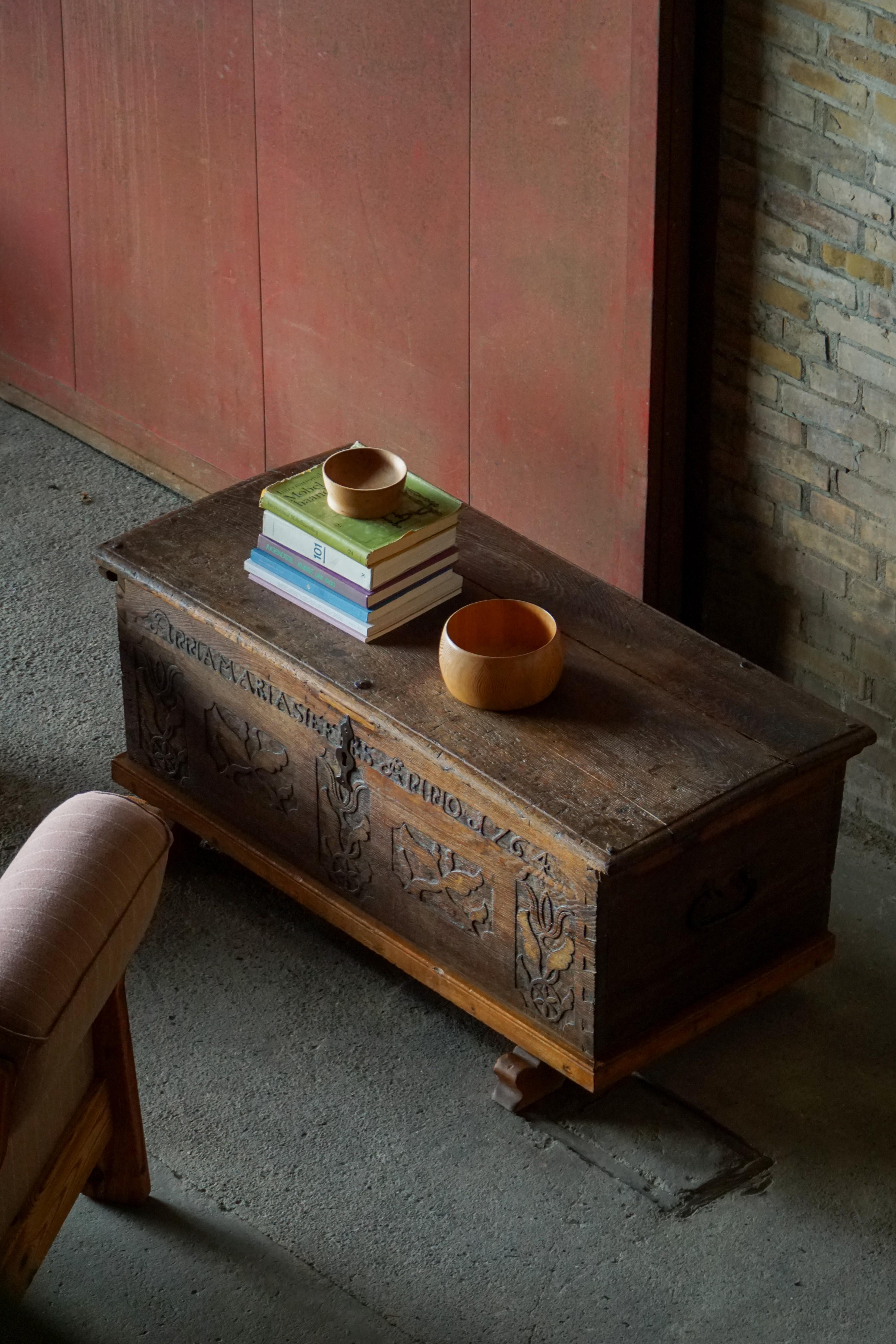 A rare and characterful Scandinavian Folk Art chest, crafted in solid oak and dated 1764. The front is richly decorated with hand-carved floral and foliate panels, flanking a central key escutcheon, and an inscribed band with the original owner’s