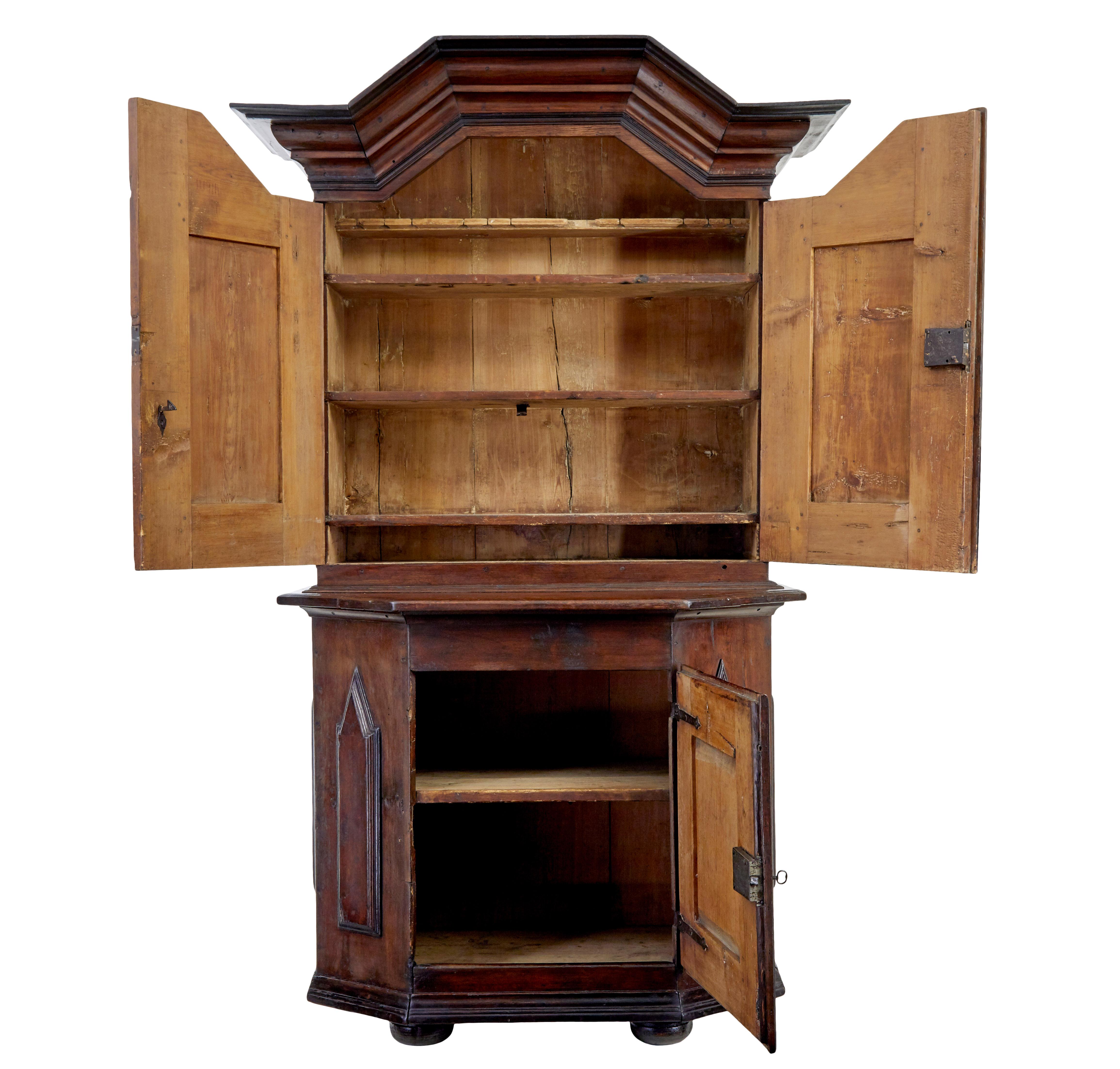 Rustic Swedish 2 part baroque cupboard circa 1790.

Stained pine baroque cupboard, a real piece of Scandinavian rustic made furniture.  Shaped cornice below and double door cupboard containing various fixed shelves.  Shaped bottom section with a