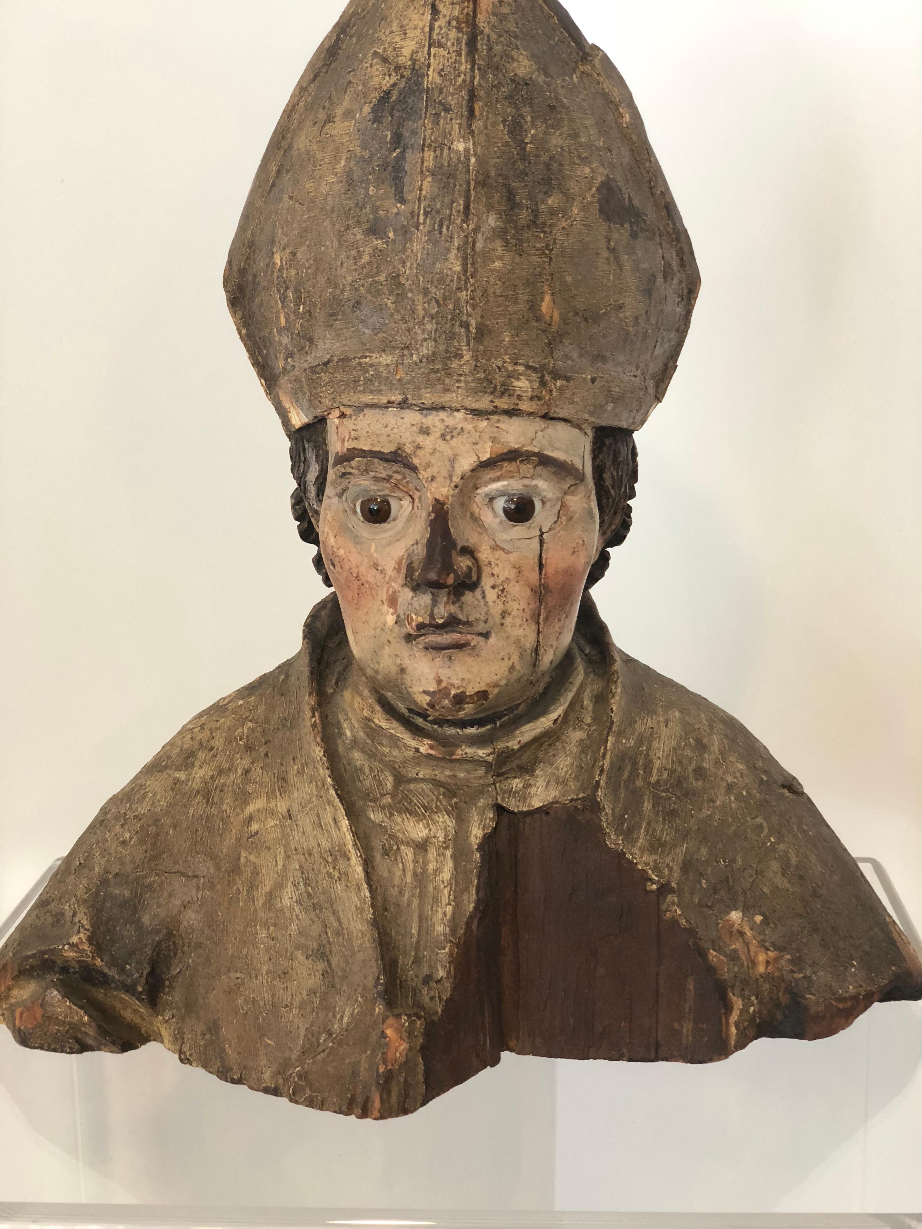 Wood Carving from the 18th Century of  a bishop or other religious figure with incredible presence and gorgeous patina. Both glass eyes are still in tact. It has some loss to the front chest and top, but this only enhances this thoughtful character