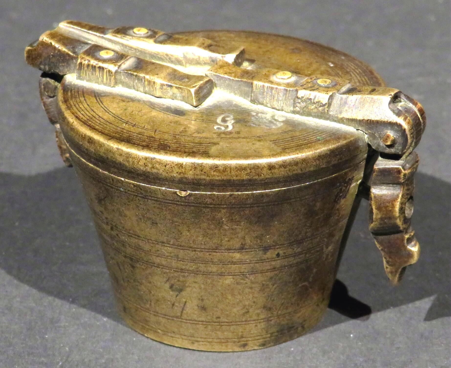 A cased set of six 18th century graduated bronze apothecary weights, each weight resting within the next, all bearing marks and encased inside the hinged master cup bearing various stamped marks including that of a crossed arrow and key denoting