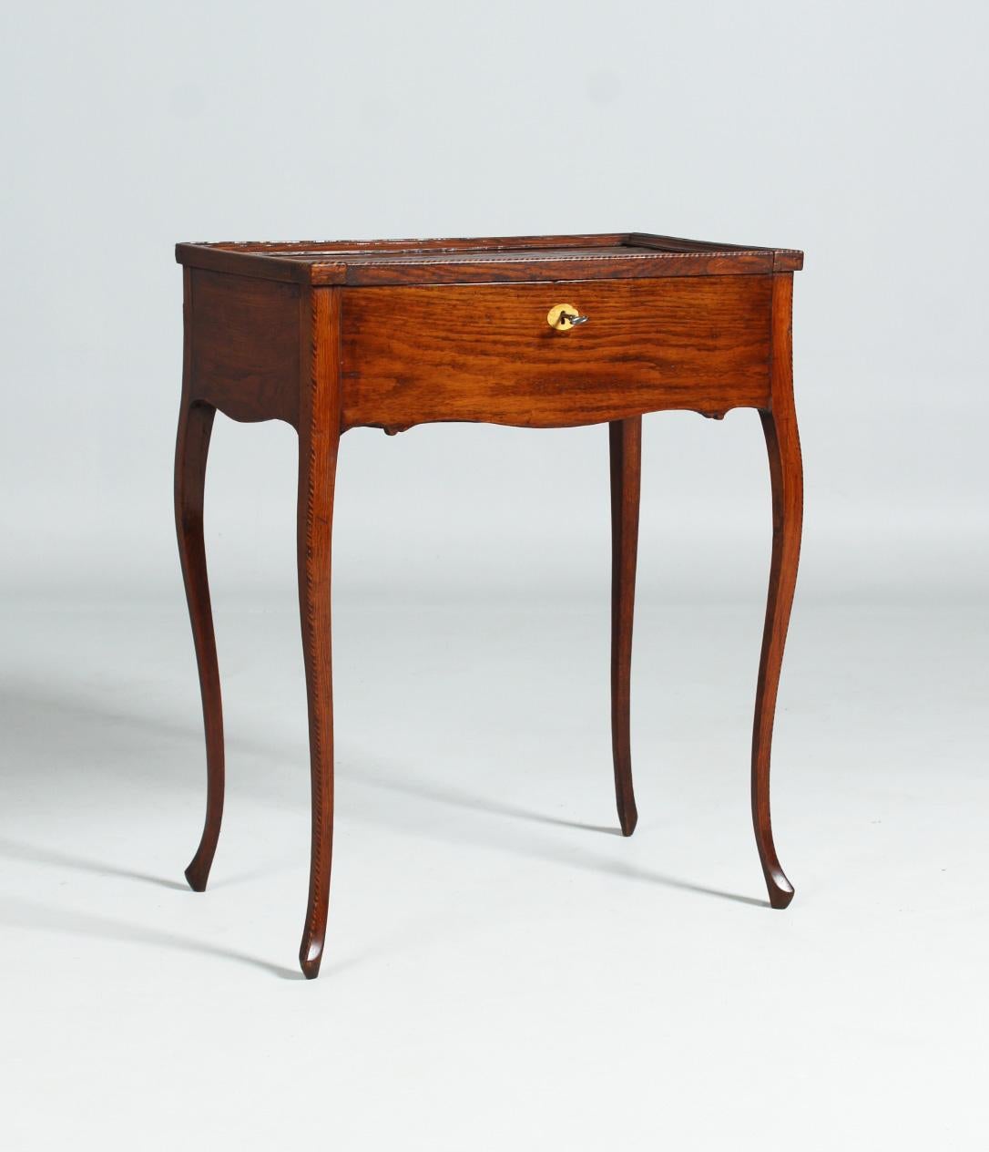 Antique side table, sewing or work table from 1786.

Dimensions: H x W x D: 78 x 62 x 39 cm

Description:
Solid oak piece of furniture standing on curved legs. The outer edge of the legs and the edge of the top is decorated by fine light-dark