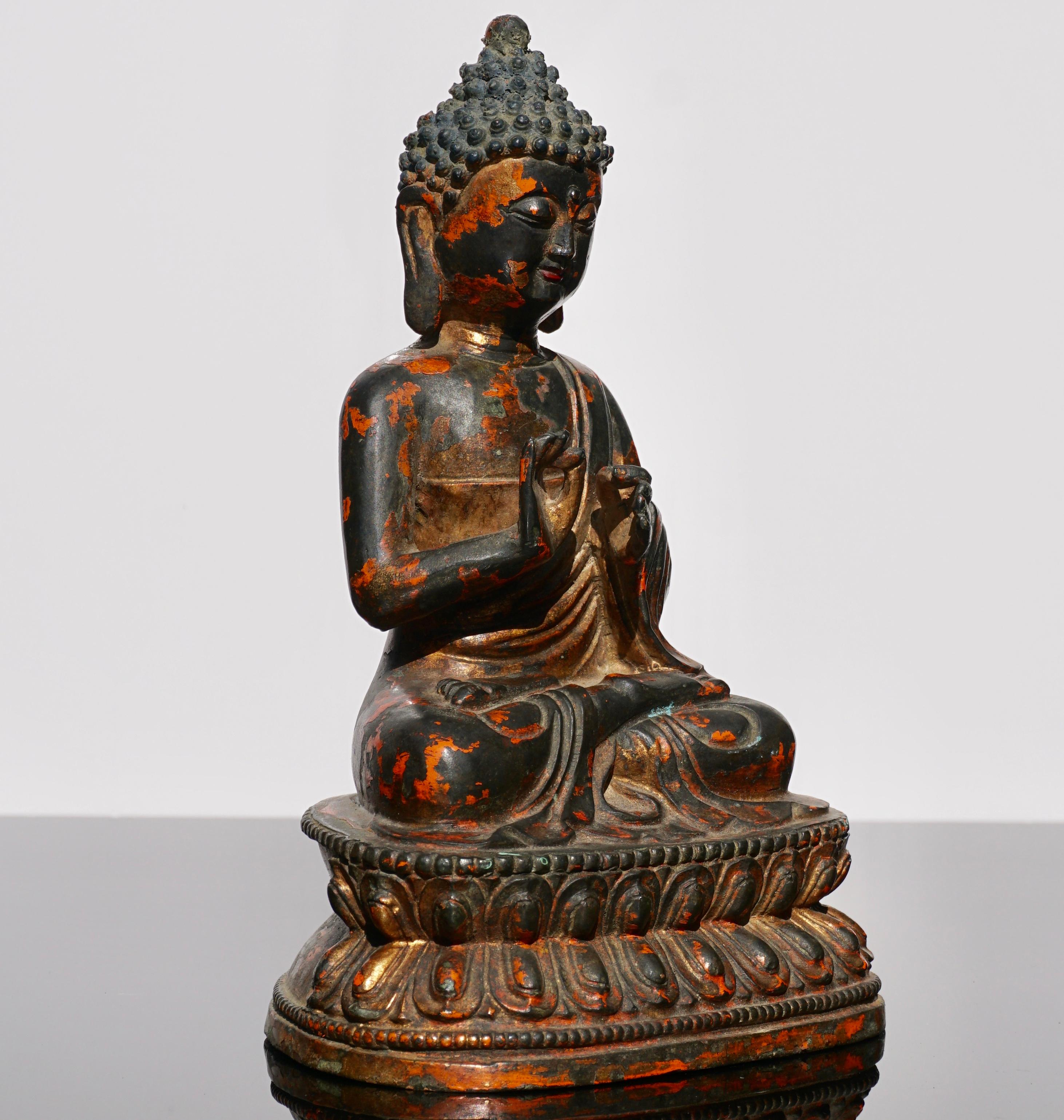 A gilt and lacquered Tibeto- Chinese bronze figure of Buddha, 18th century.

The figure is shown seated in dhyanasana on a double lotus pedestal and holding his right hand in vitarka mudra, the gesture of teaching. The eyes are cast downwards