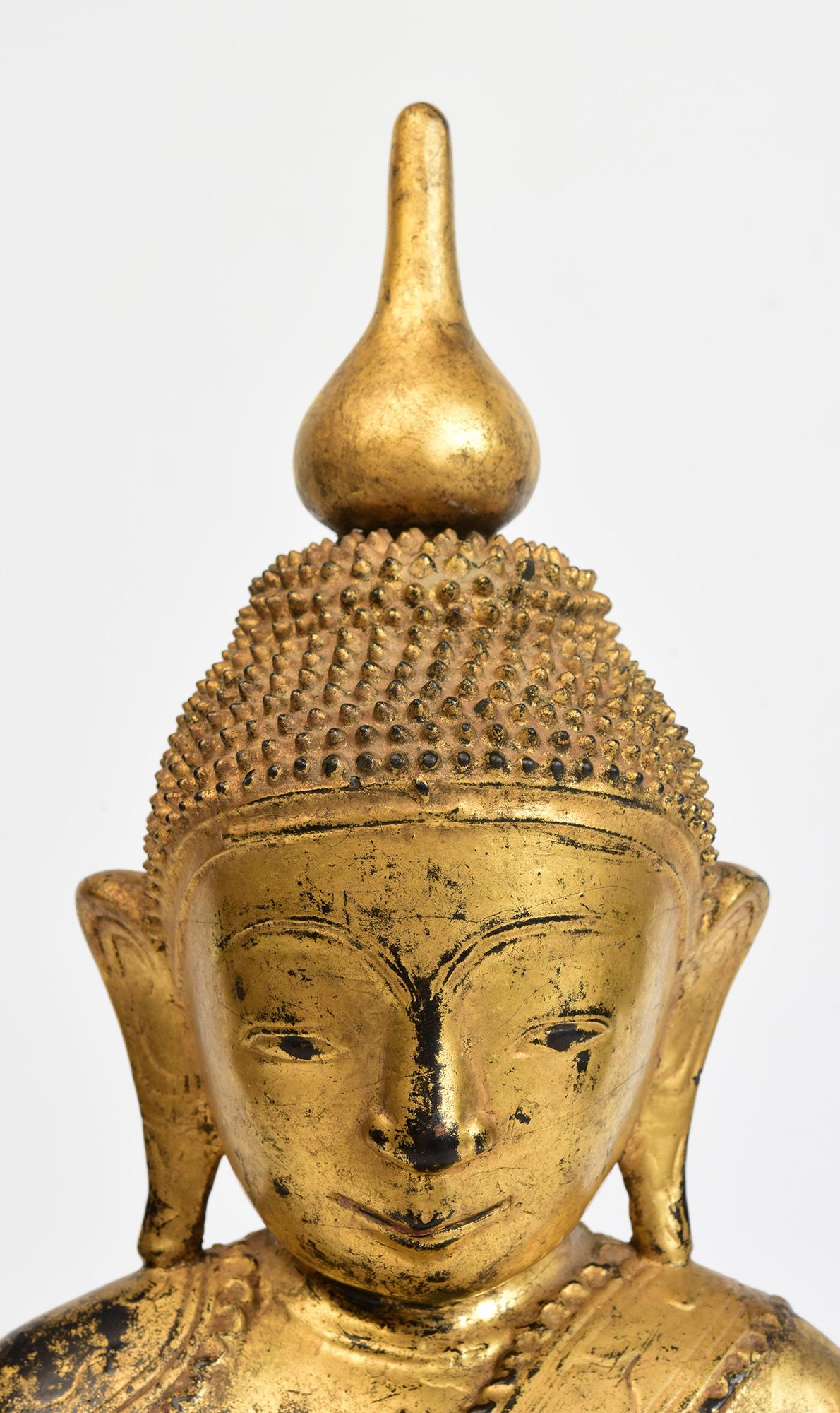 Antique Burmese wooden Buddha sitting in Mara Vijaya (calling the earth to witness) posture on a base with gilded gold.

Age: Burma, Shan Period, 18th Century
Size: Height 41.6 C.M. / Width 18.3 C.M. / Depth 10.4 C.M.
Condition: Nice condition