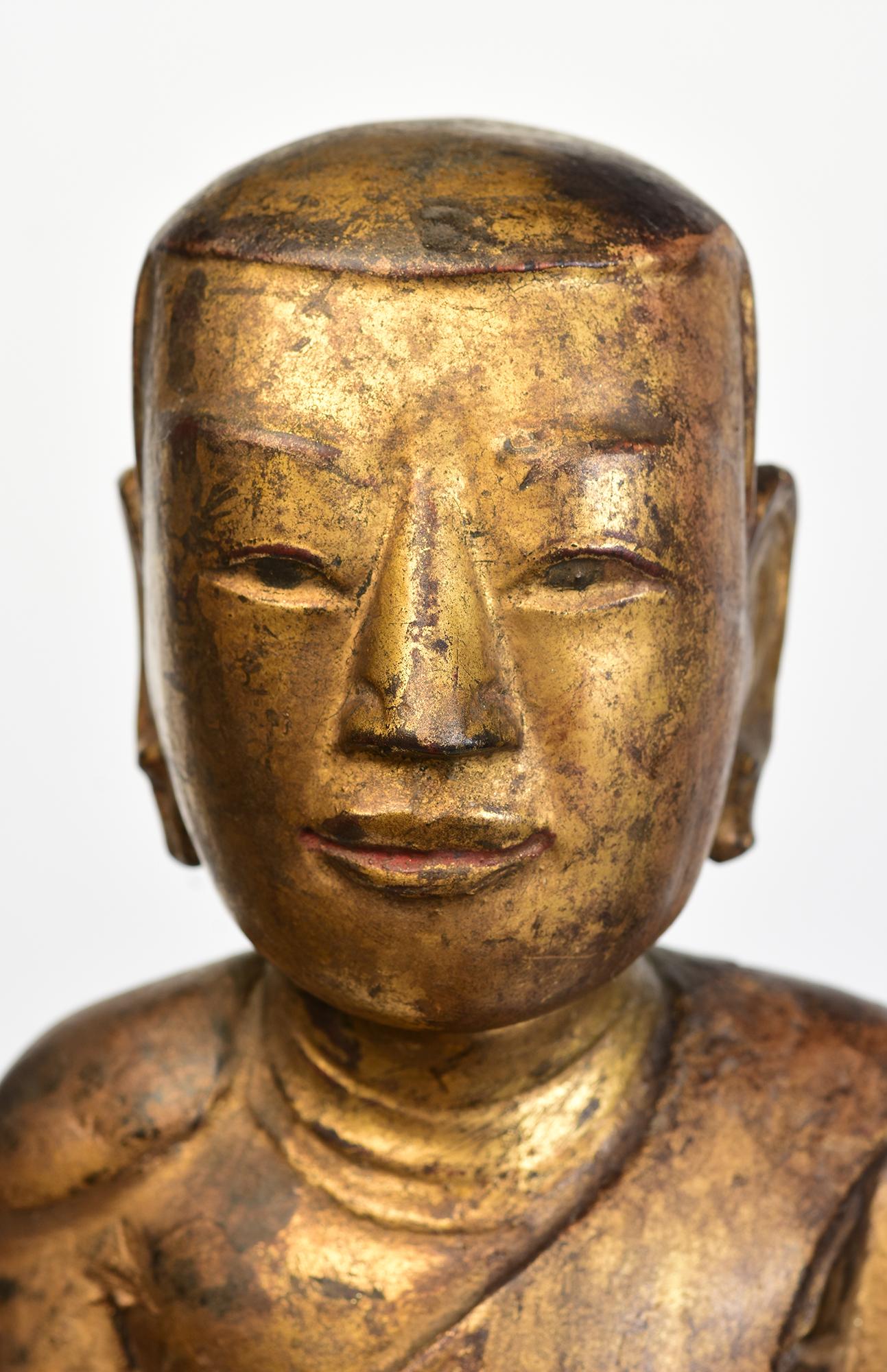 Antique Burmese wooden disciple holding bowl standing on lotus base with gilded gold. 

Age: Burma, Mandalay Period, 19th Century
Size excluding stand: Height 48.3 C.M. / Width 12 C.M. / Depth 10.4 C.M.
Height including stand: 61.8 C.M.
Condition: