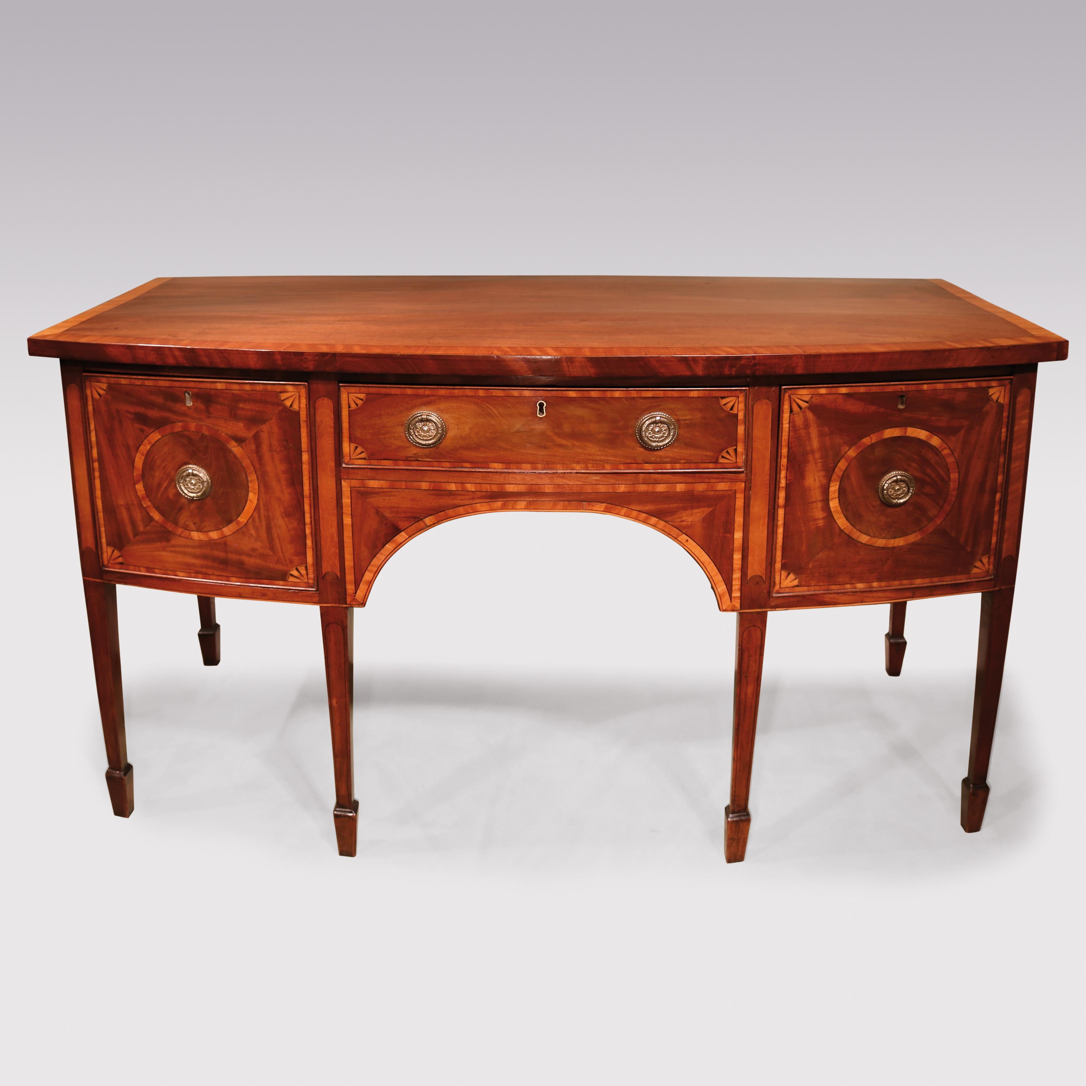 Un beau buffet en acajou de la fin du 18ème siècle, de style Sheraton, à façade en arc, avec un plateau en bois de satin à bandeaux croisés, au-dessus d'un tiroir à couverts central, avec un tablier arqué en onglet en dessous, flanqué de tiroirs en
