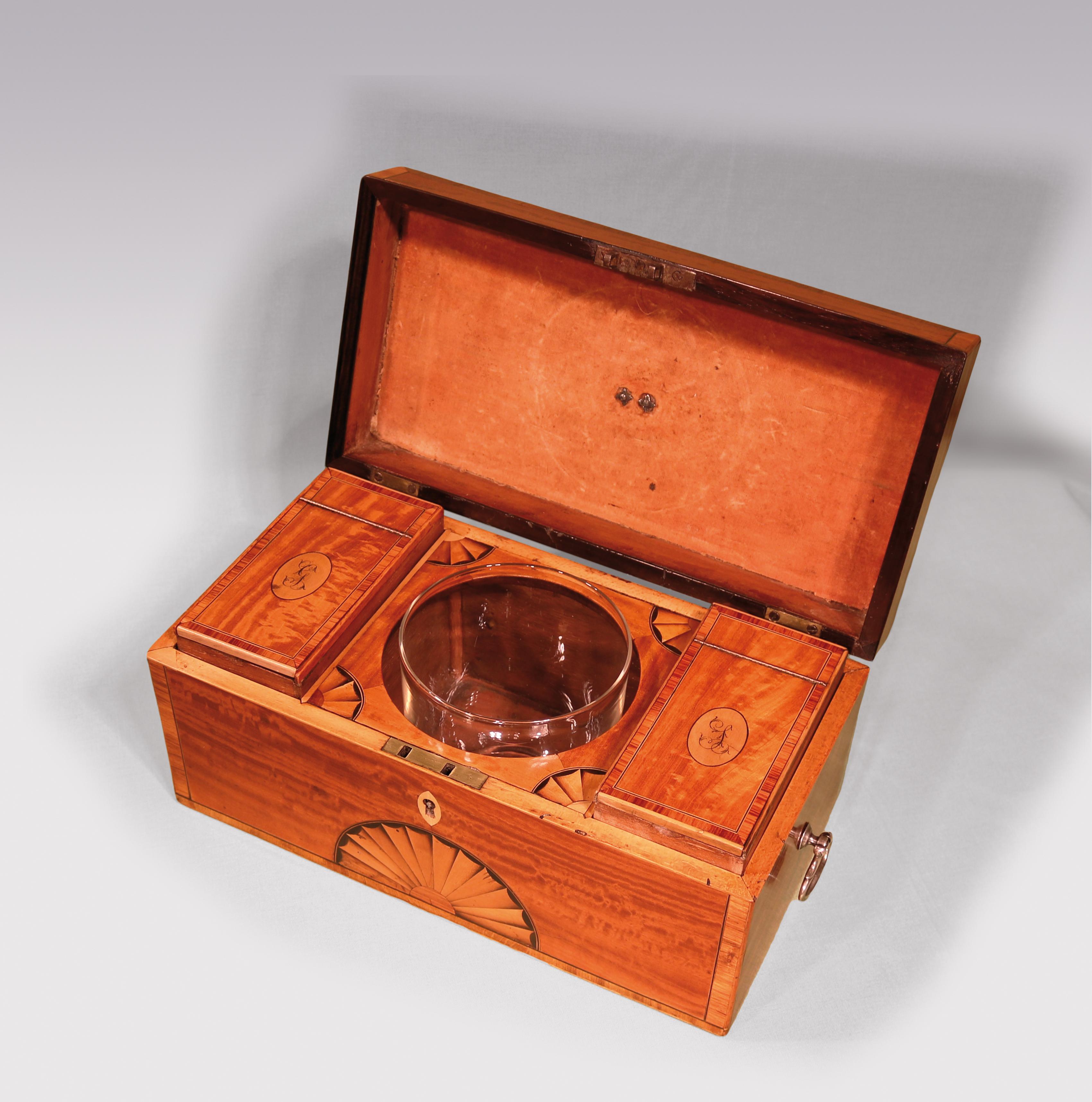 A late 18th century Sheraton period tulipwood crossbanded satinwood Teacaddy, having oval fan inlays & silver handles. The interior fitted with compartments with initialled lids & central mixing bowl compartment.