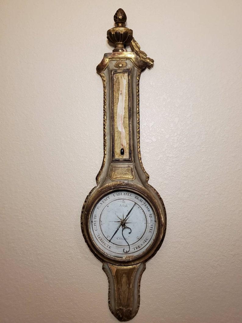 A magnificent nearly 250 year old Louis XVI period (1774–1793) hand carved and painted parcel gilt French wall thermometer and barometer signed Carcano.

Exquisitely hand-crafted in Paris, France in the second half of the 18th century, exceptionally