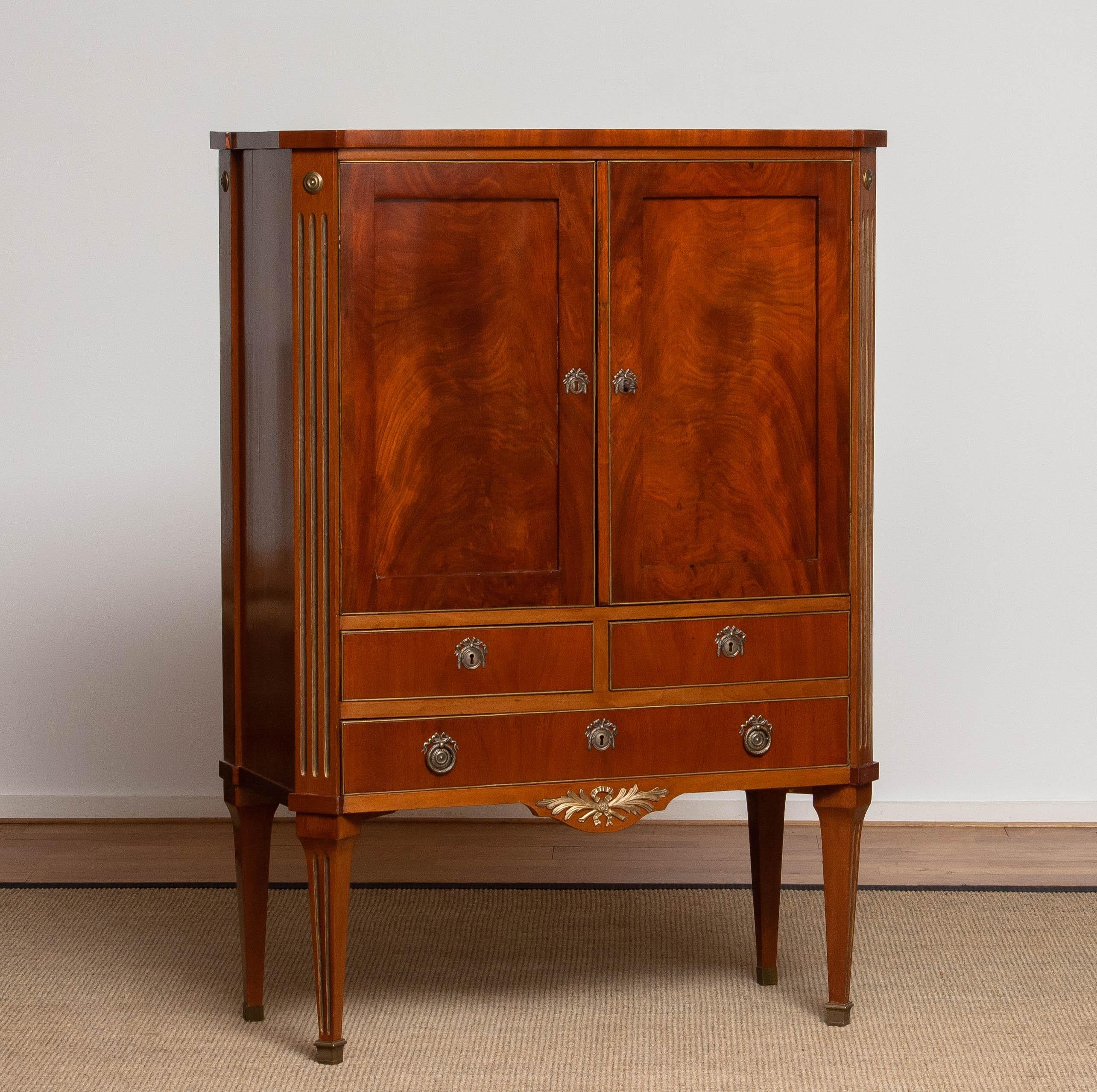 Beautiful and slim mahogany veneered, pine, Gustav / Louis XVI cabinet with brass inlay and mounted details build by craftsmen in Baltic / Swedish regions early 18th century. 
Allover this cabinet is in good condition and is steady on her legs.