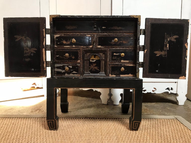This old wooden chest was probably a jewelry box back in the day. It was painted in black then hand painted with decor and organic forms throughout. The two wooden front doors open to a series of drawers small enough for jewelry or something
