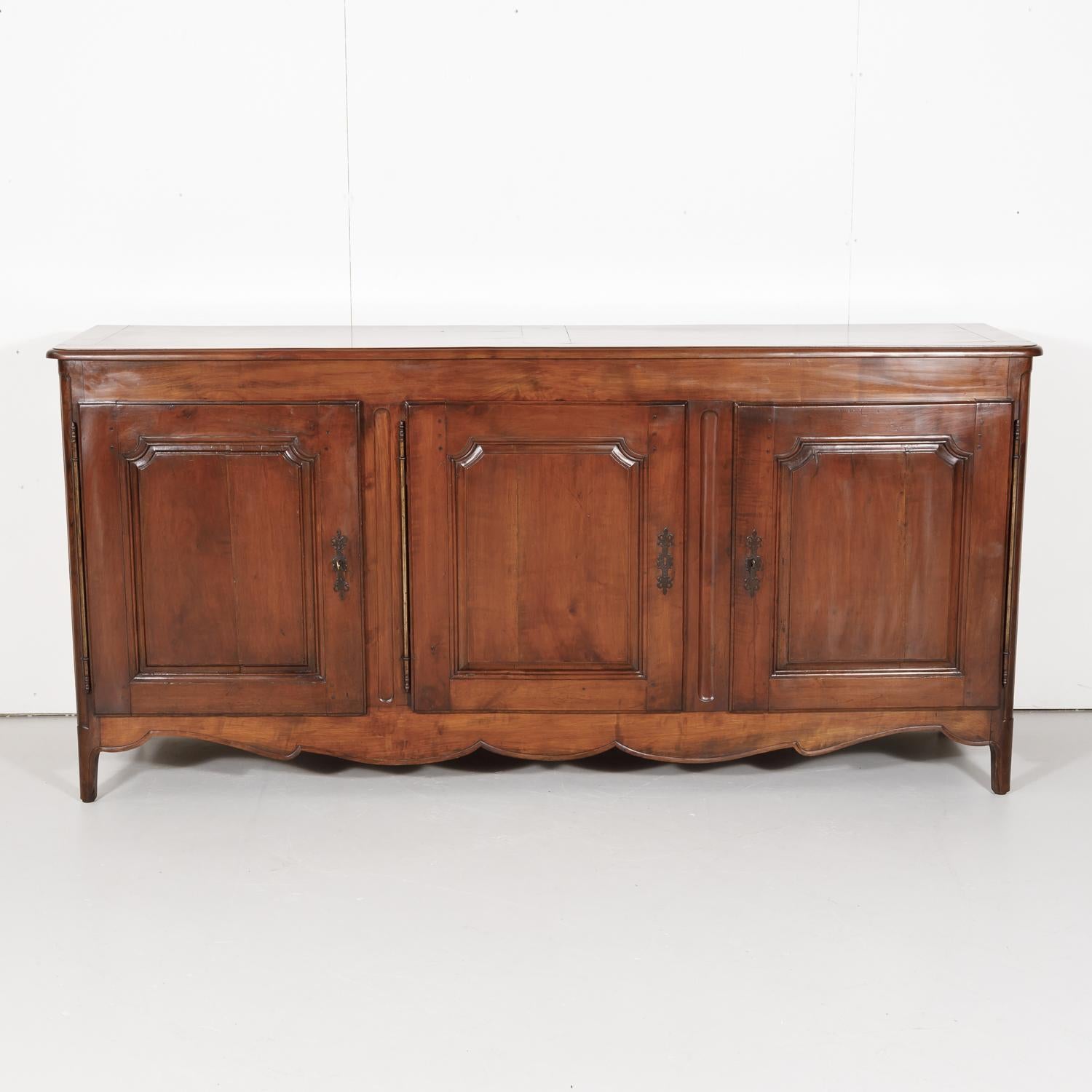 An 18th century Louis XV - Louis XVI Transition period solid cherry enfilade buffet handcrafted by skilled artisans from Toulouse during the French Transition period (1750-1775), having three panel doors that open to reveal plenty of storage. The