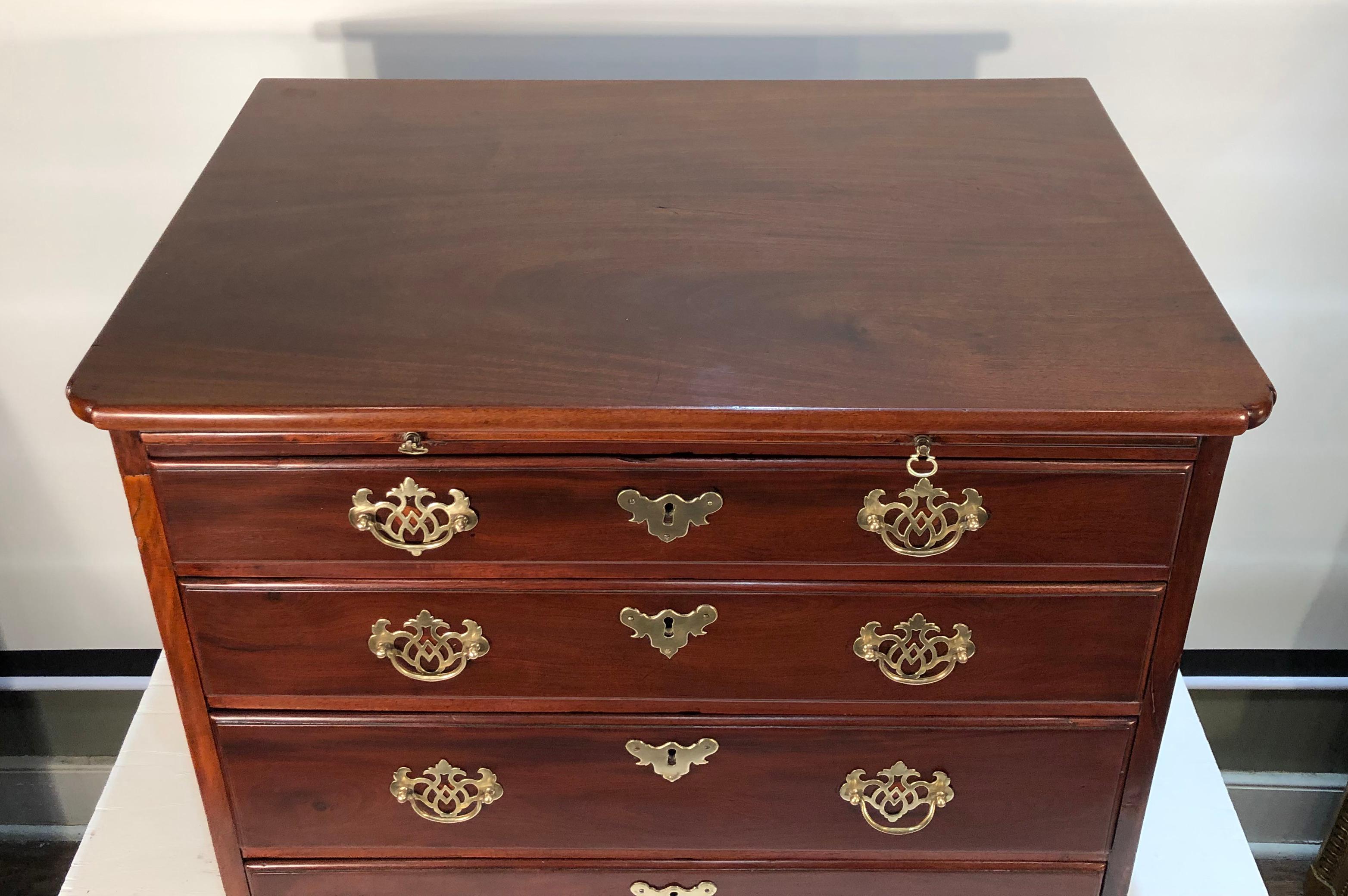 This handsome 18th century solid mahogany English bachelor’s chest has a one board top over the brushing slide. There are 4 graduating drawers ending in original bracket feet. The rich patina and color make this a very beautiful chest. The pulls are