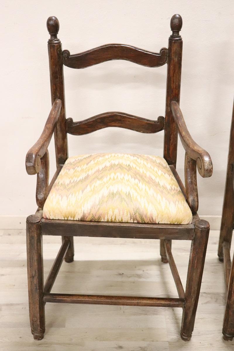 Beautiful 18th century of the period Louis XVI Italian antique rustic set of 2 armchairs in solid walnut wood. These armchairs are very simple and essential. The seats are wide and comfortable, padded with fabric that features a Missoni-like