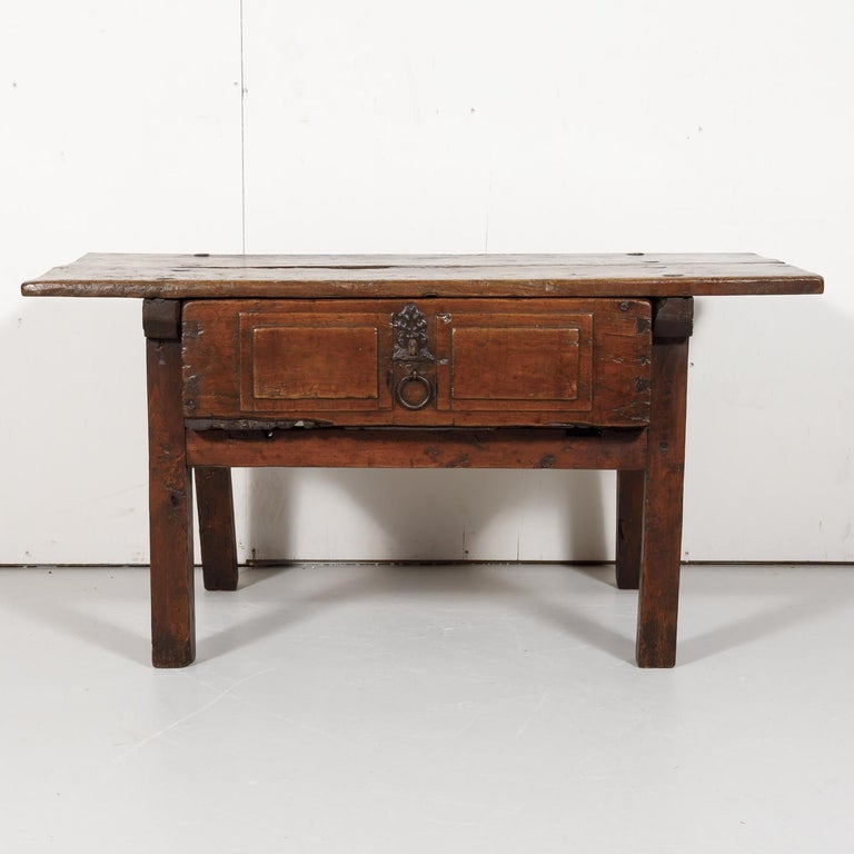 A rustic early 18th century side table handcrafted of solid walnut near Valencia, Spain, circa 1720s. Soundly constructed having a rectangular plank top above a large drawer with original iron ring pull and raised on mortised splayed square legs.