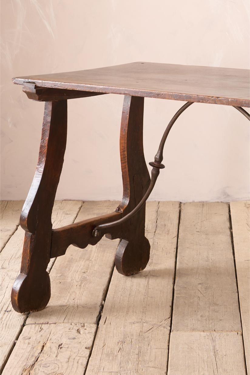 This is a stunning genuine 18th century Spanish walnut table. The top is a single piece of walnut full of character and patina. The base design of the legs is gorgeous and have honest old patina and minor restoration. The iron work stretcher also