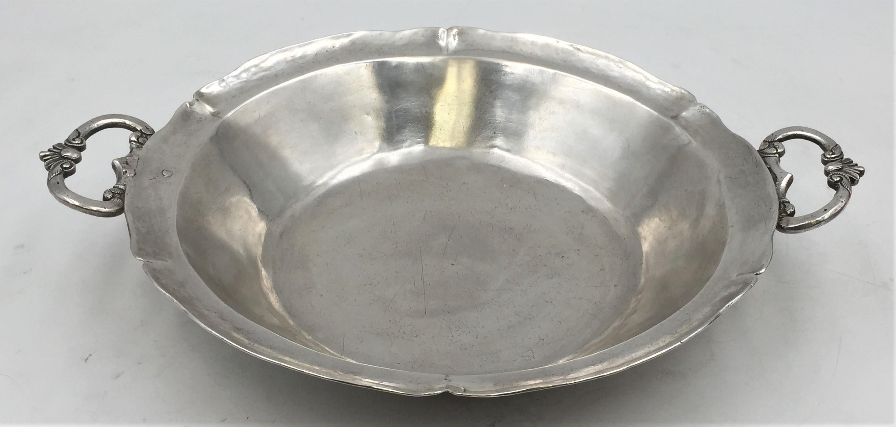 South American silver bowl from the 18th century, apparently unmarked, from the Colonial era, with ornate handles on either end and beautiful curved lines around the rim. It measures 11'' from handle to handle by 1 3/4'' in height, and weighs 14.7