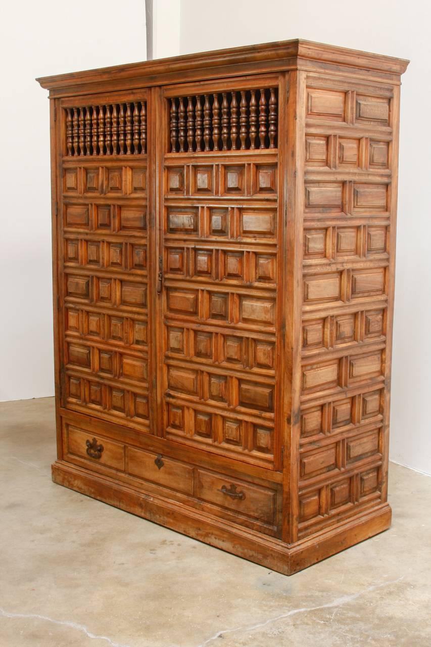 Grand 18th century Spanish Armario or wardrobe armoire constructed from walnut. Features a coffered case fronted by two large doors with windows and turned spindle grills. This massive cabinet made in the Baroque taste features beautiful walnut