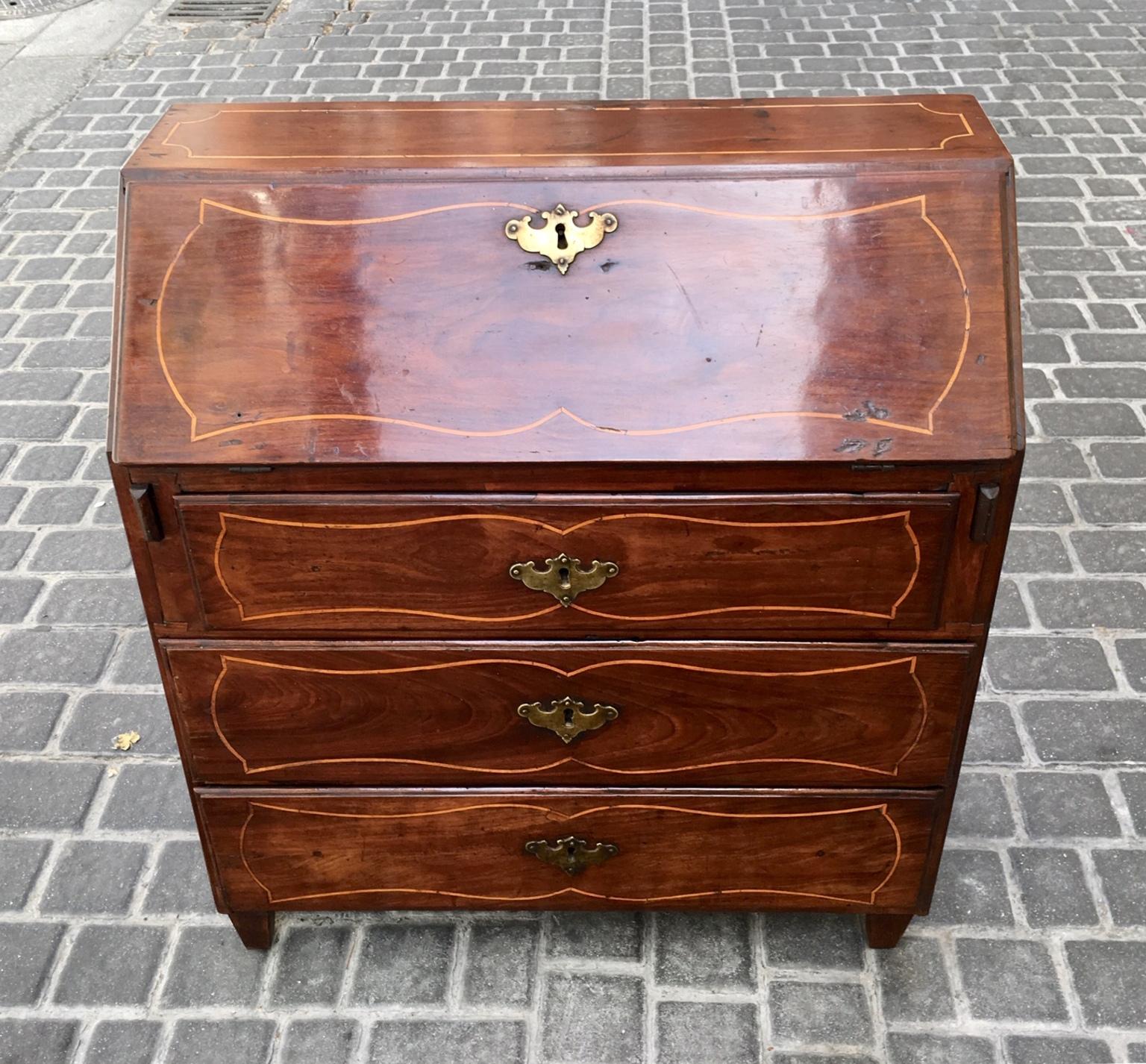 Elegant Spanish Bureau of the 18th century, at the time Carlos IV, its size is smaller than usual, to be transported on trips, it is made of mahogany wood with inlaid marquetry in boxwood.
It consists of three drawers with original bronze