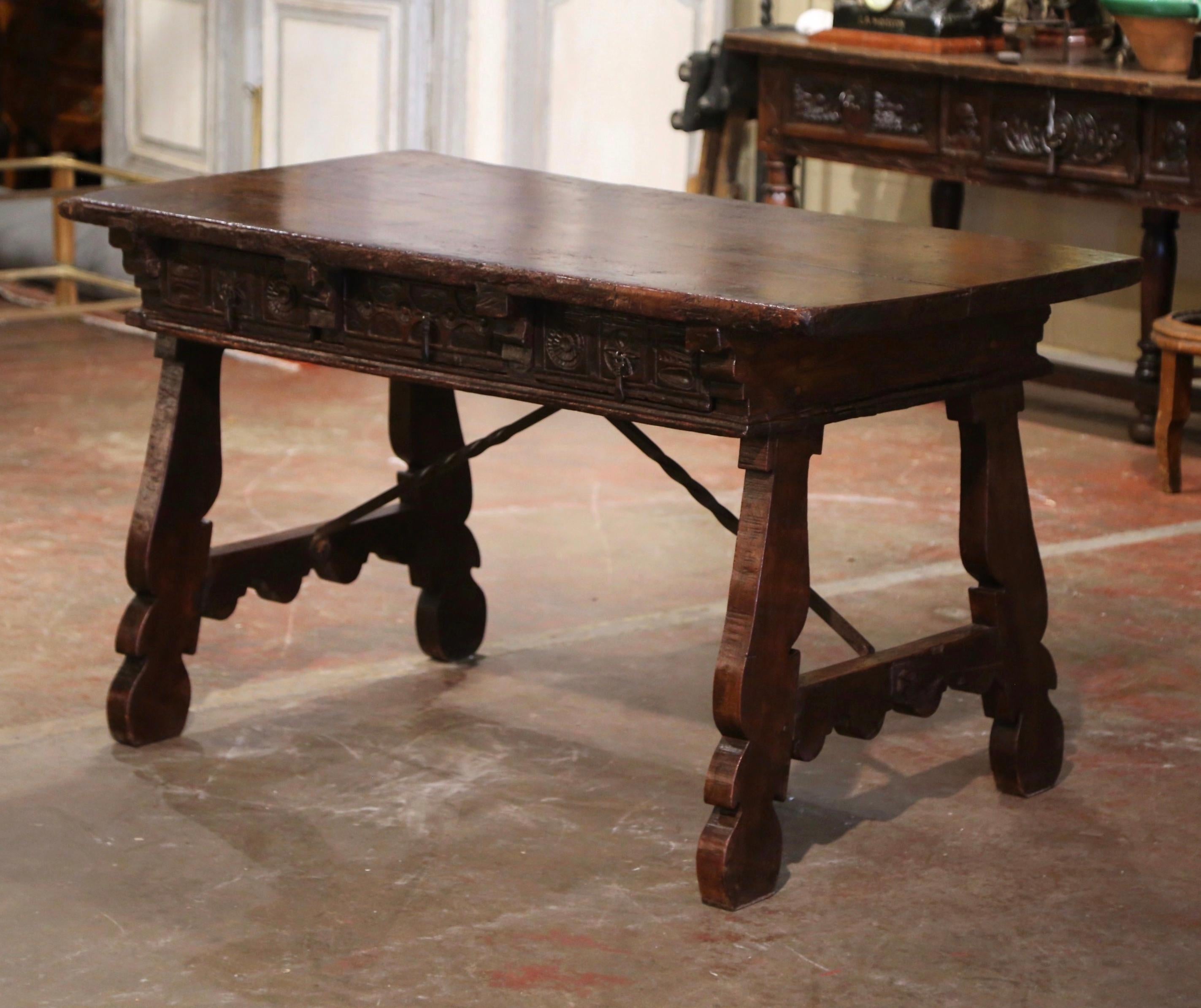 Add an elegant focal point to your study or library with this antique Spanish desk. Carved in Spain circa 1750, the trestle table stands on two intricate carved legs, connected with a thick, forged and twisted wrought iron stretcher. The top built