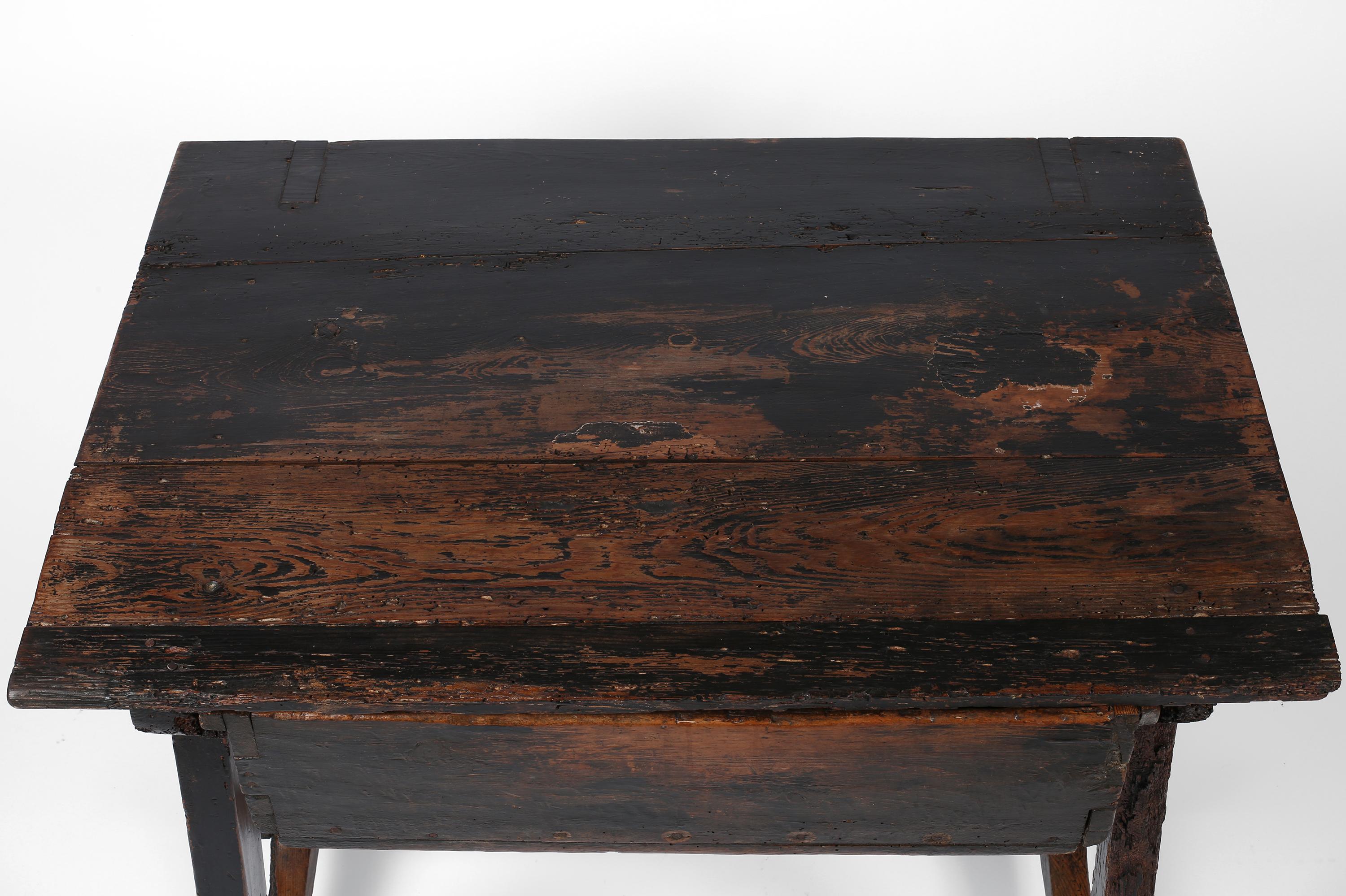 A dramatic 18th century side table, deep console or small desk in blackened and heavily patinated pine timber. Retaining much of its original paint and with many characterful later repairs/additions, the table features a typical X-frame design,