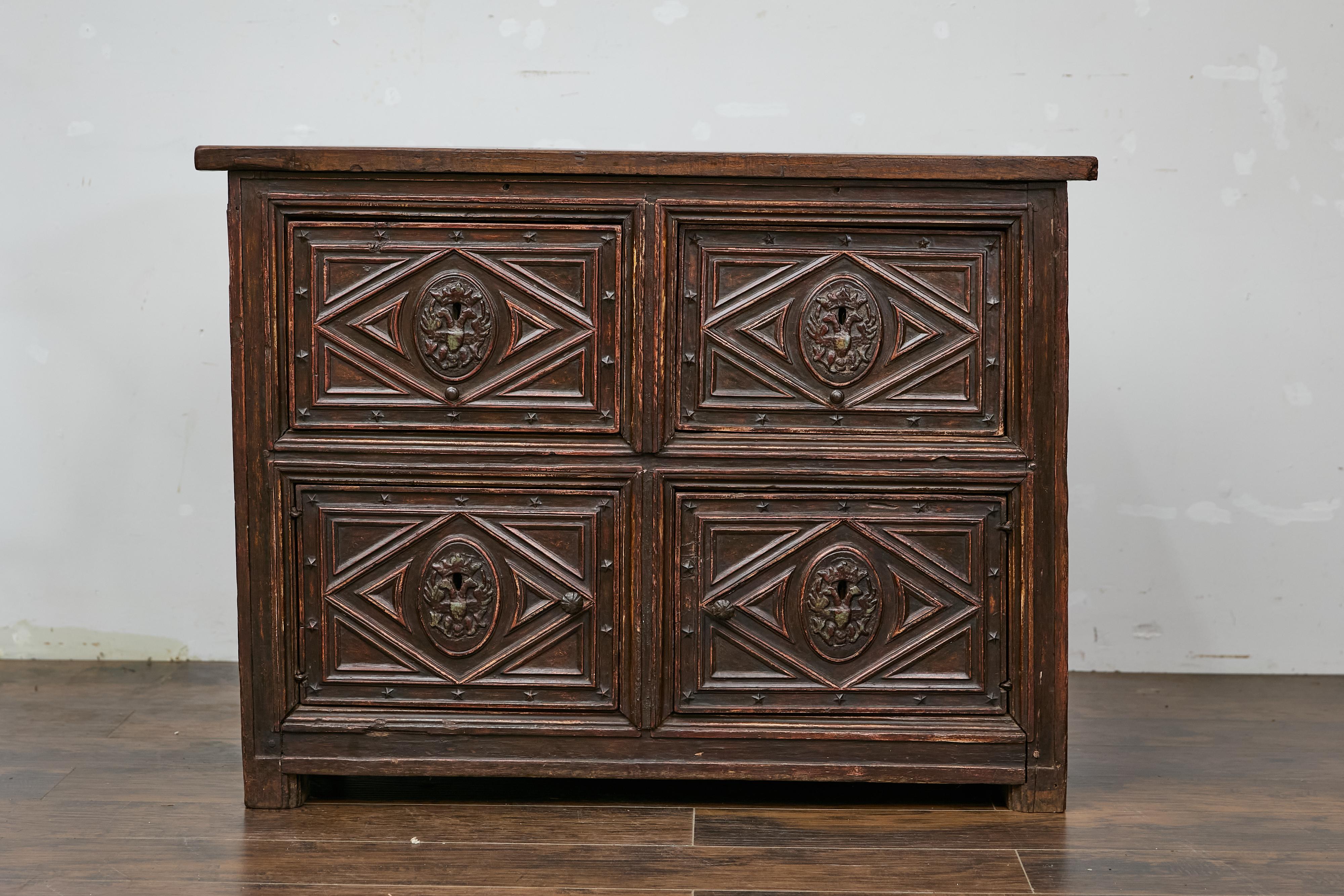 A Spanish Colonial wooden sideboard from the 18th century with carved geometric front and two drawers over two doors. This exquisite 18th-century Spanish Colonial sideboard showcases a striking geometric carved front that immediately captures