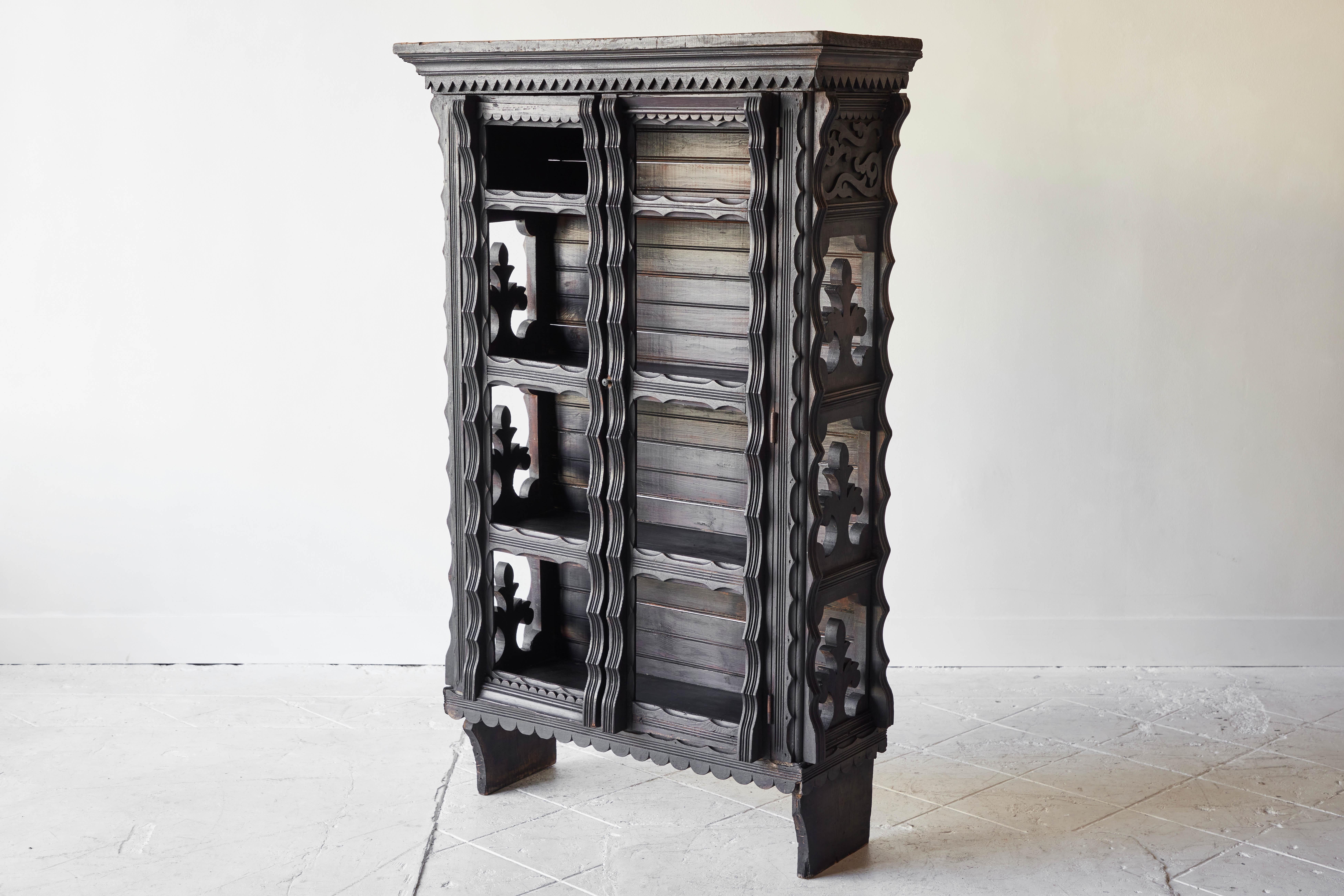 Decorative wood carved shelving unit from Spanish Colonial Mexico features an ornate pattern with beautifully carved designs on the front and sides. It is the perfect piece to display valuables or books as the interior has 3 shelves and the doors