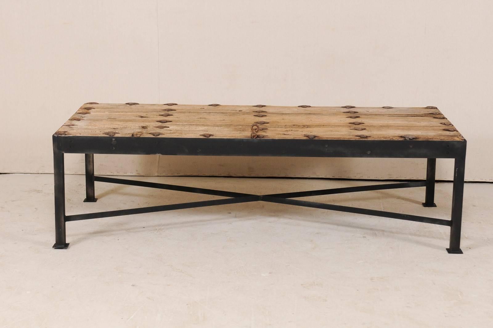 This is a custom coffee table made from an 18th century Spanish door. This fantastic coffee table has been fashioned from an 18th century Spanish door, with it's elongated wood planks adorn with their original rows of iron grommets and hardware, set