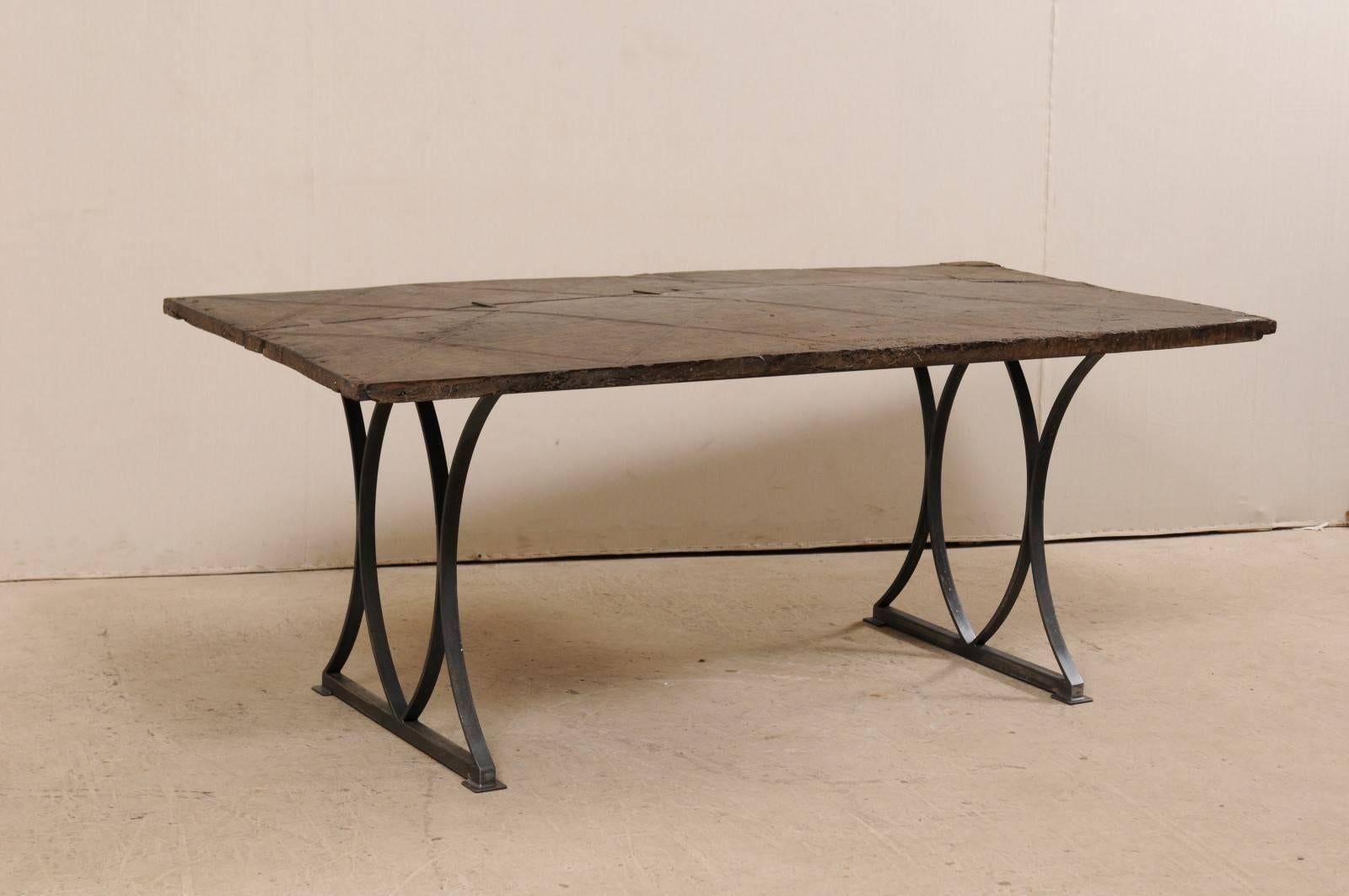 A custom table with an 18th century Spanish hand-carved door top. This rectangular-shaped table has been fashioned by setting an 18th century Spanish door onto a custom iron base. The door top of this table has been hand-carved with a criss-cross