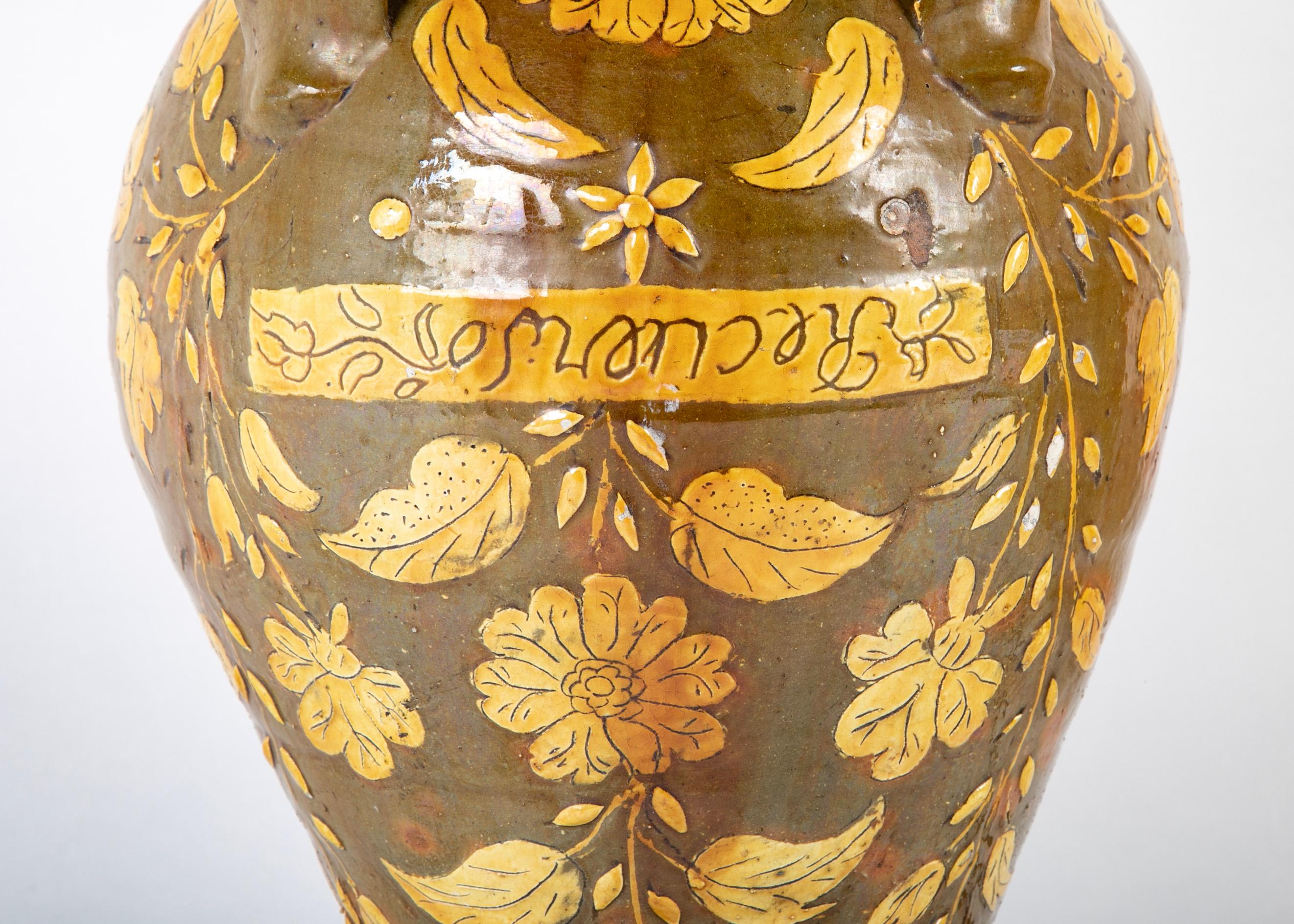 Very interesting 18th century Spanish ceramic wine or oil storage jar with wonderful olive green glaze with raised leaf and floral design in yellow. The word 'Recuerdo', which translates to 'Memory' curiously written upside down in the center. A