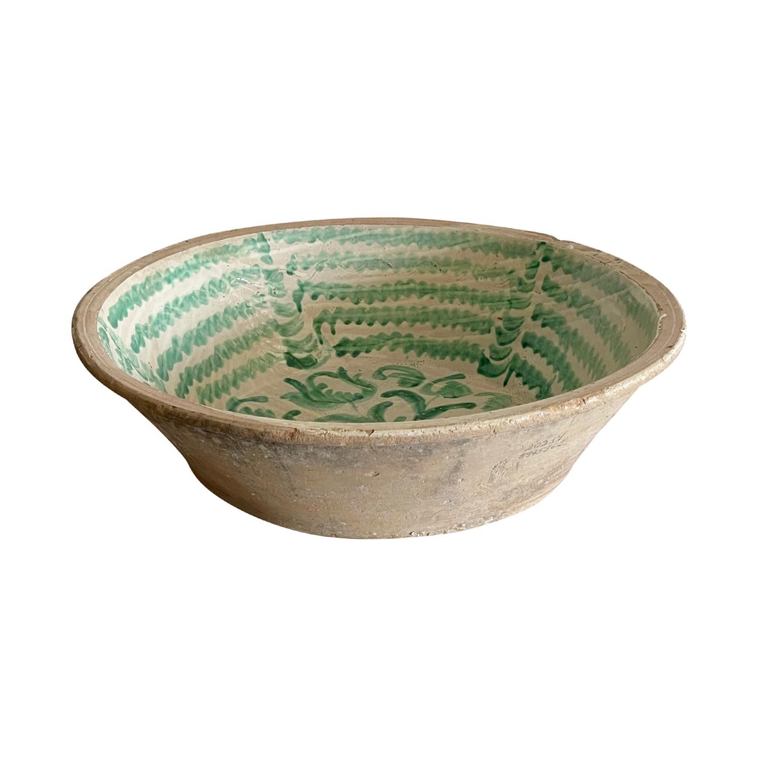 A very large antique Spanish Lebrillo mixing bowl in earthenware, made of hand crafted terra cotta, originating from Granada, Spain. Featuring a glaze decoration in the typical Morisco green over a milk-white glaze. A floral motif is painted onto