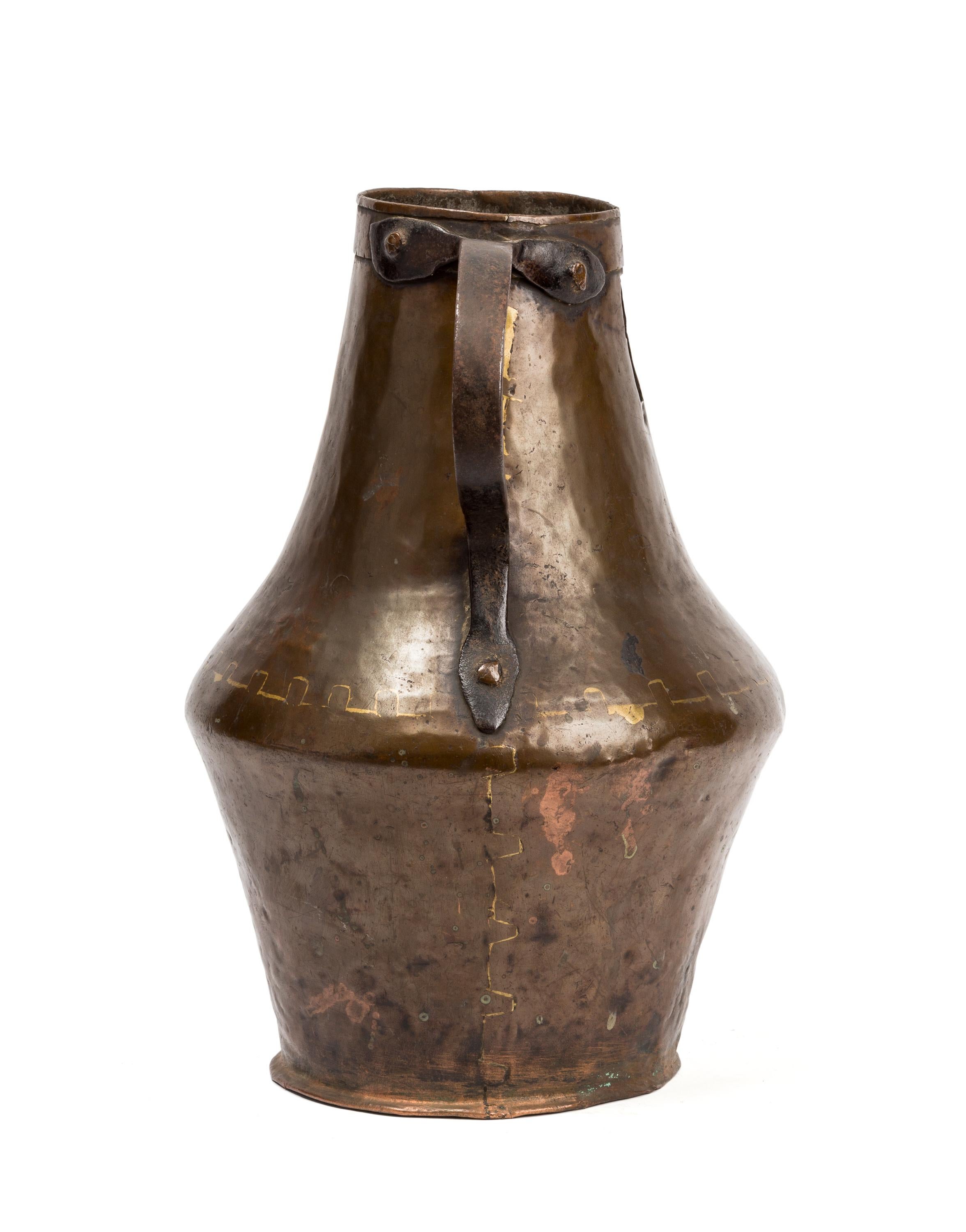 Hammered, riveted and soldered in 18th century Spain, this copper container was made for common household use, but with its sculptural form, rich color and patina of age it surpasses its rough beginnings to become a thing of beauty. The pitcher sits